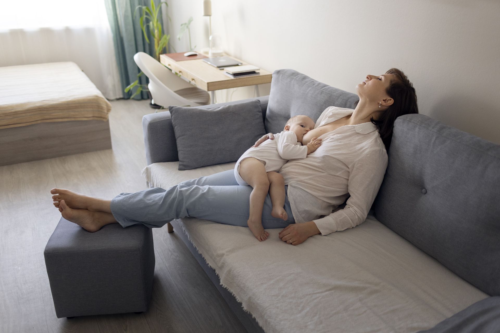 a mother breastfeeding her baby while resting on the couch