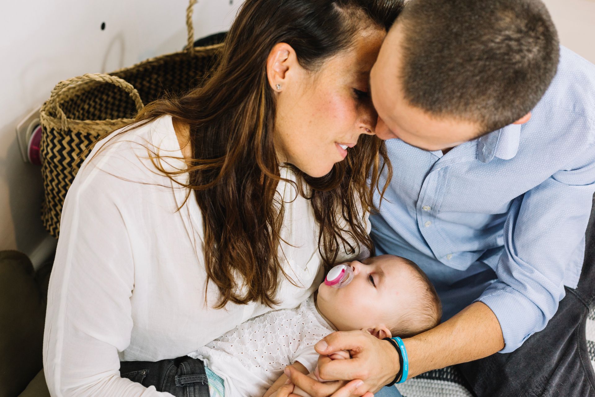 A couple sits close together while holding newborn baby