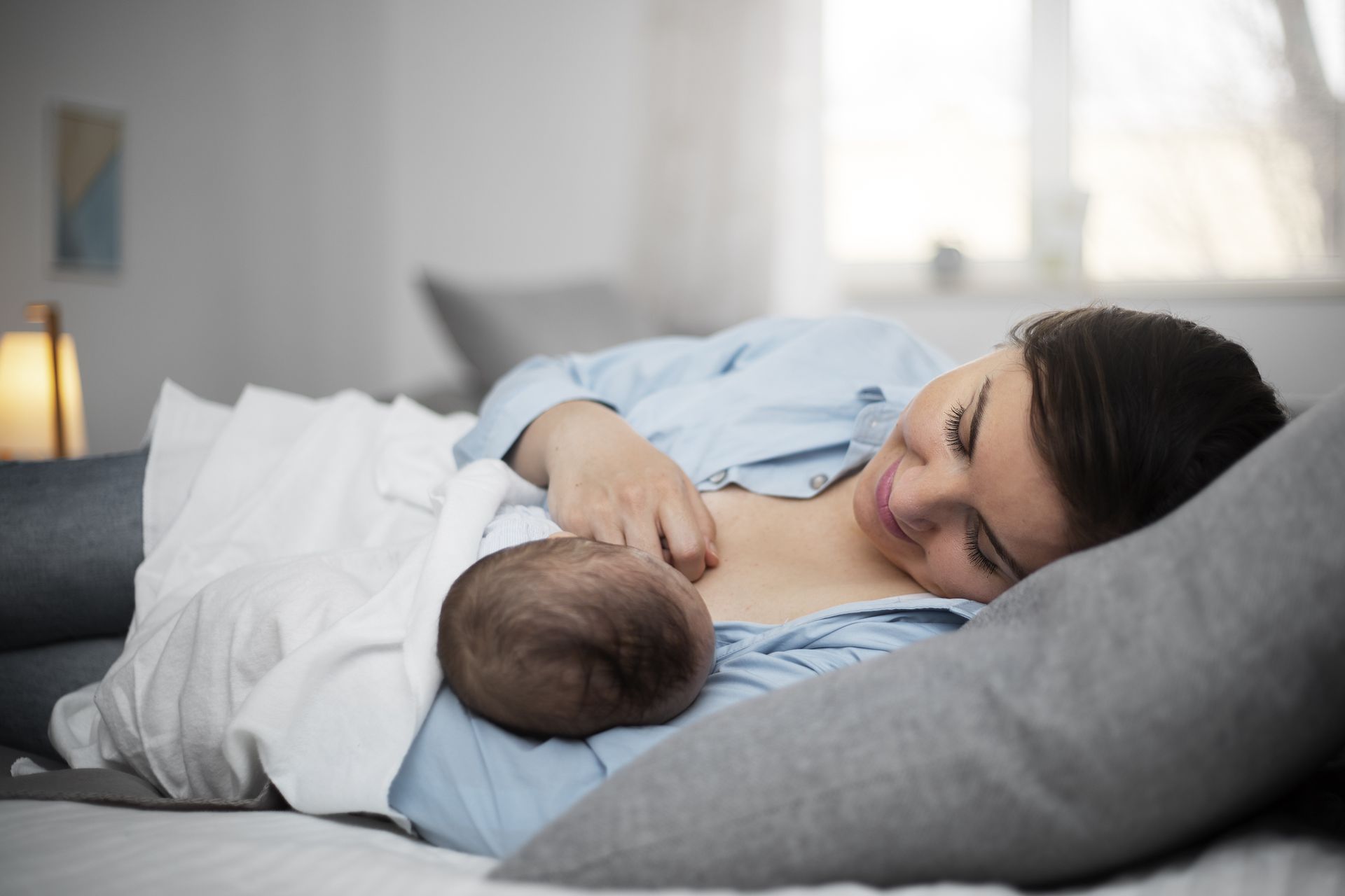 new mom laying on her side breastfeeding baby
