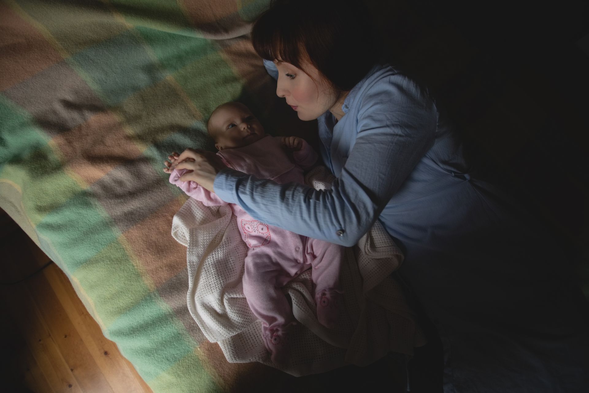 A mother and her newborn baby laying in bed at night