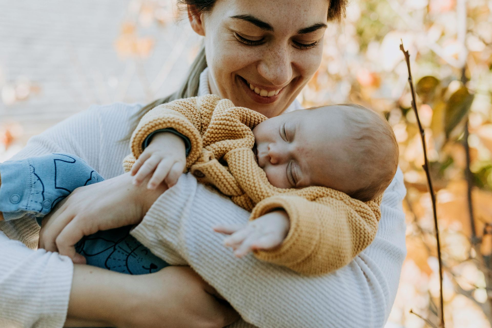 A postpartum mom holding her newborn baby and smiling