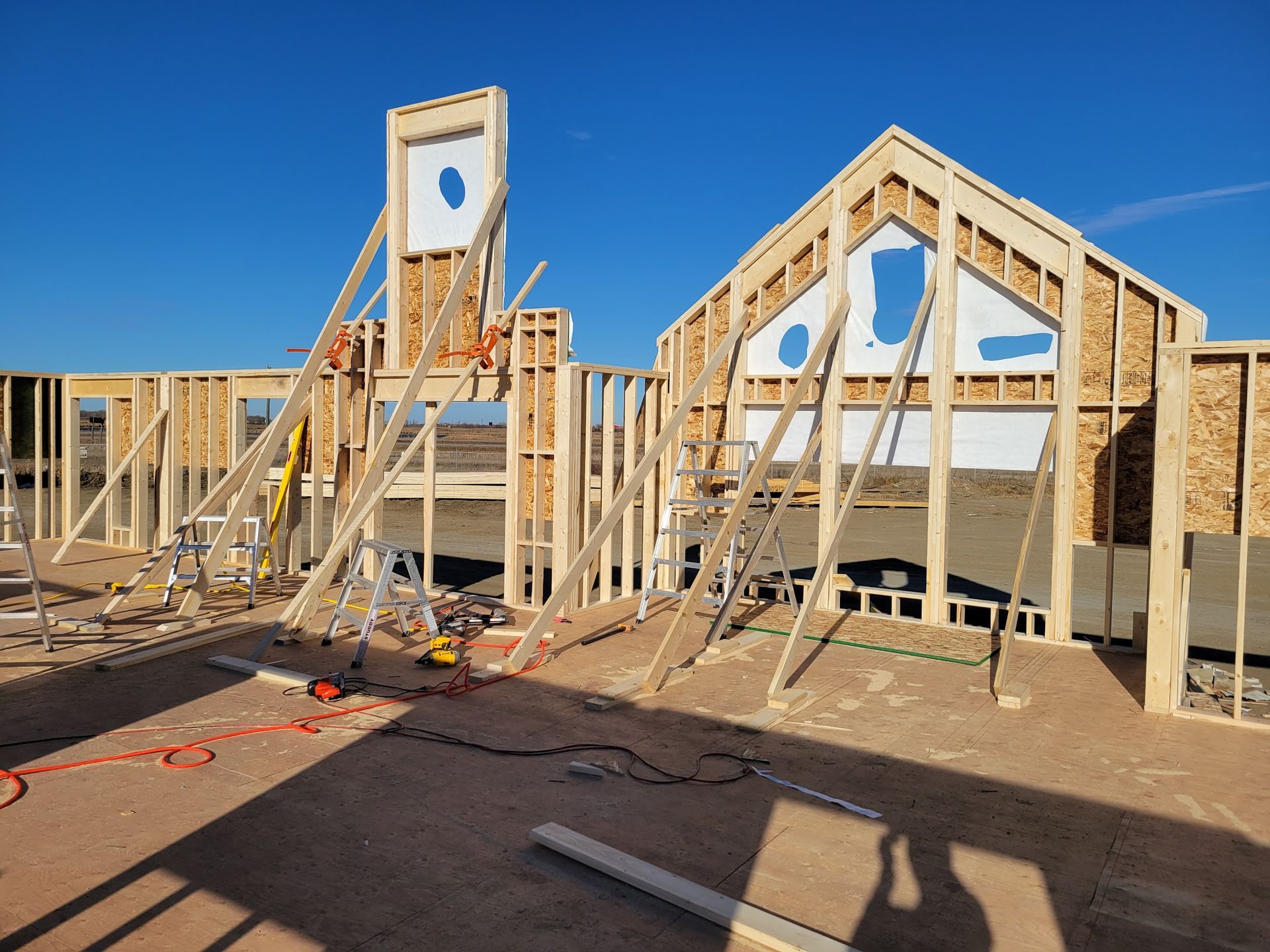 A house is being built with wooden beams and a blue sky in the background.