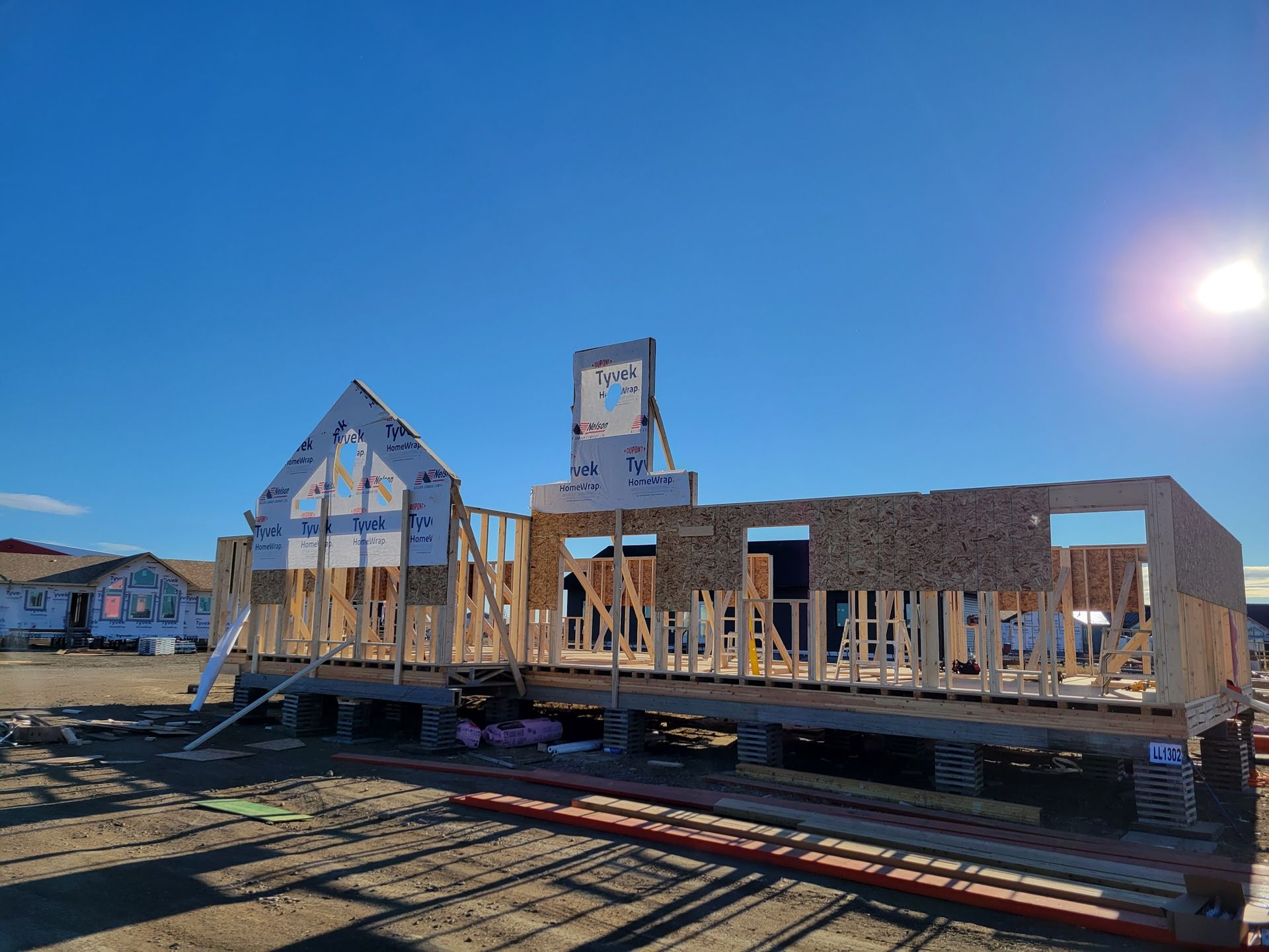 A house is being built in a field with a blue sky in the background.