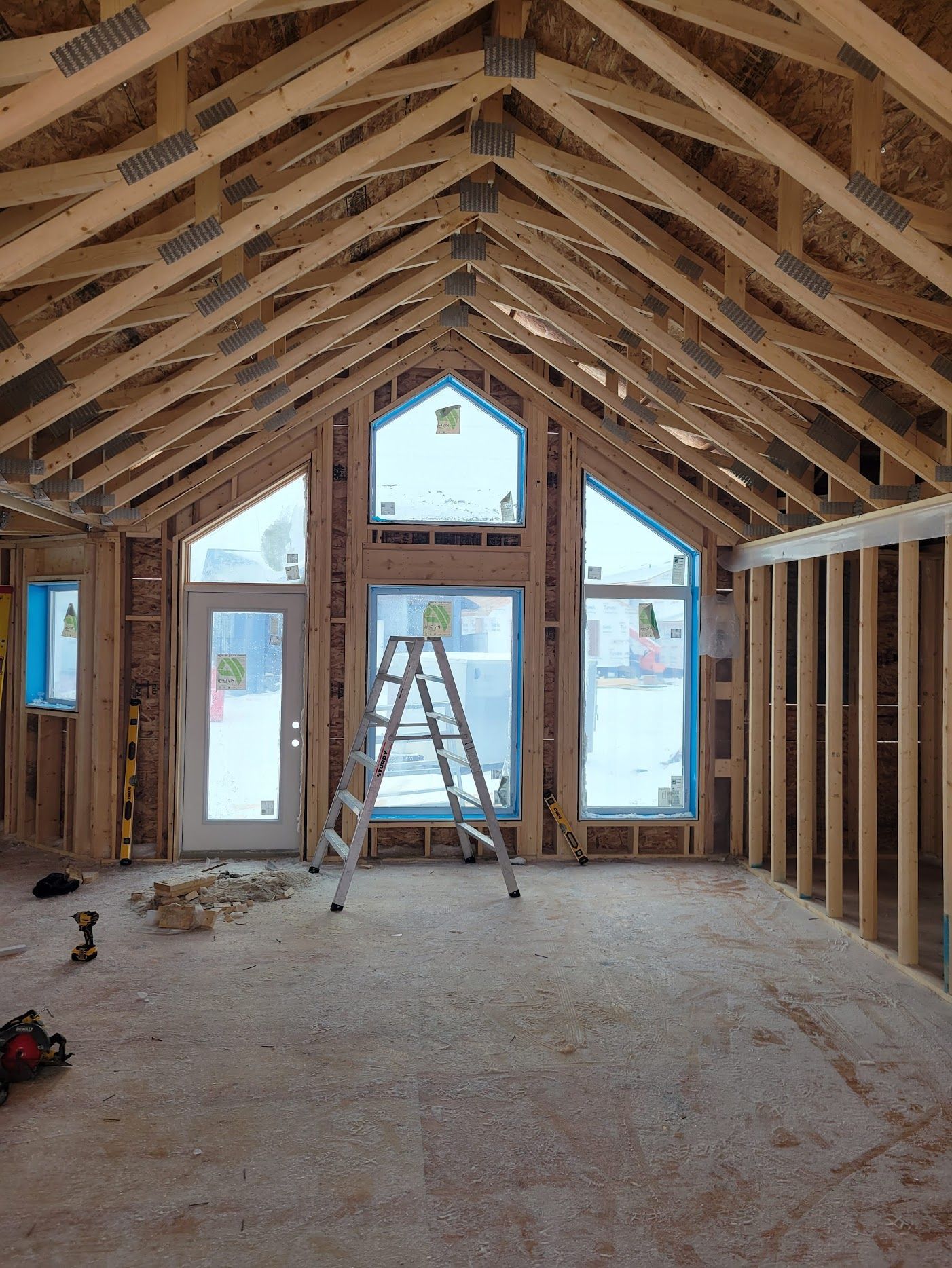 The inside of a house under construction with a ladder in the middle of the room.