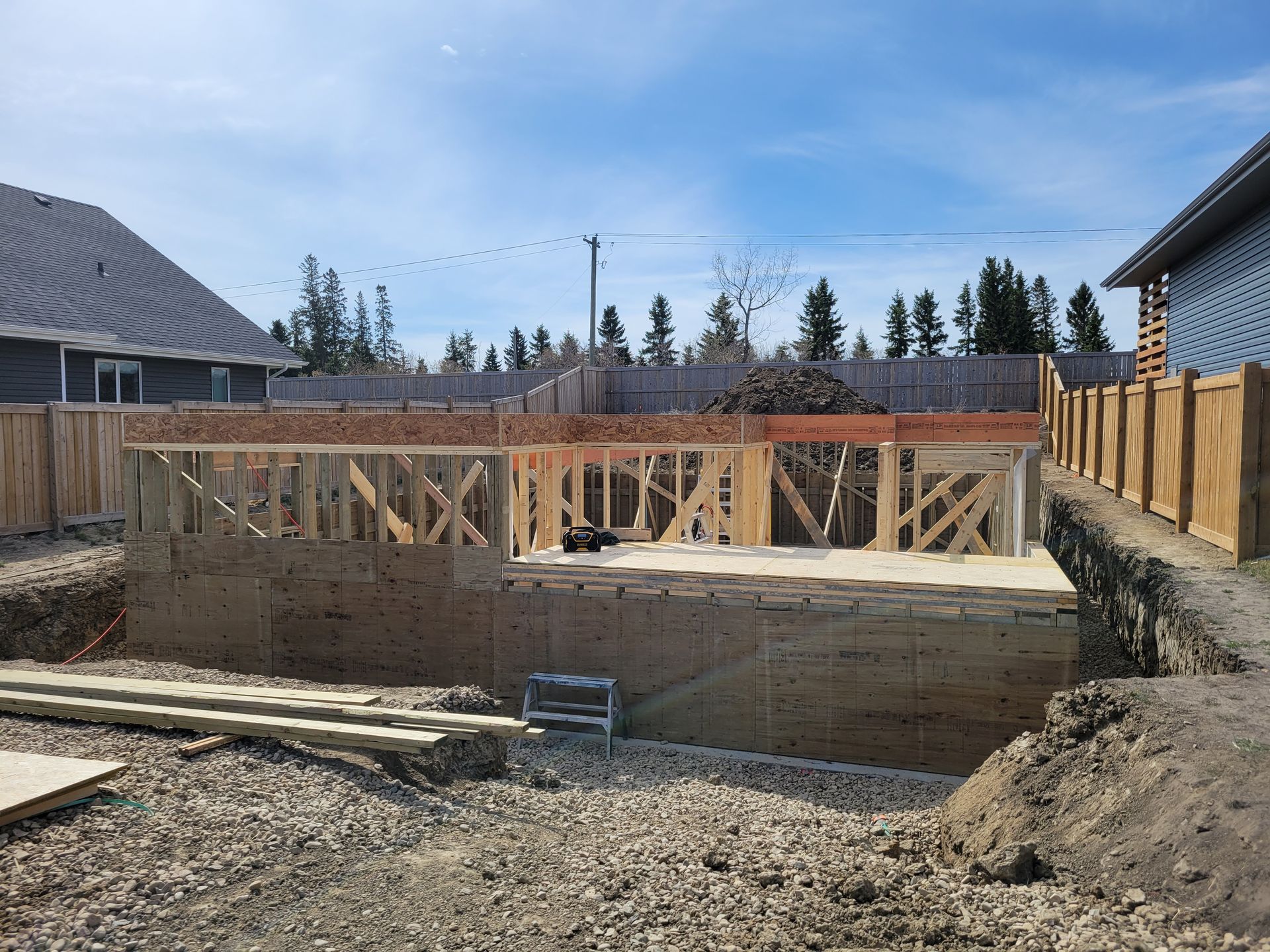 A house is being built in a backyard with a large hole in the ground.