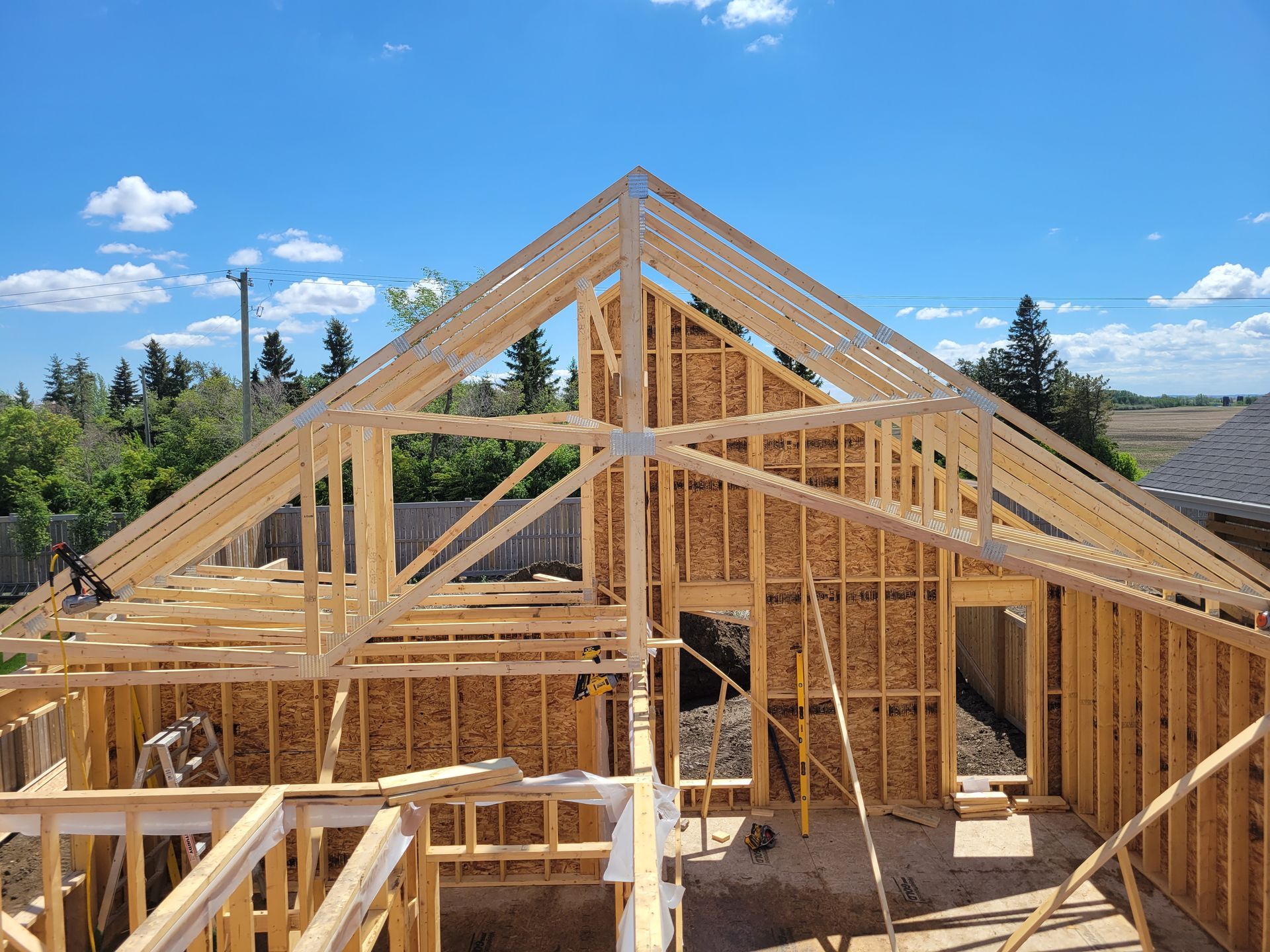 A wooden house is being built with a blue sky in the background.