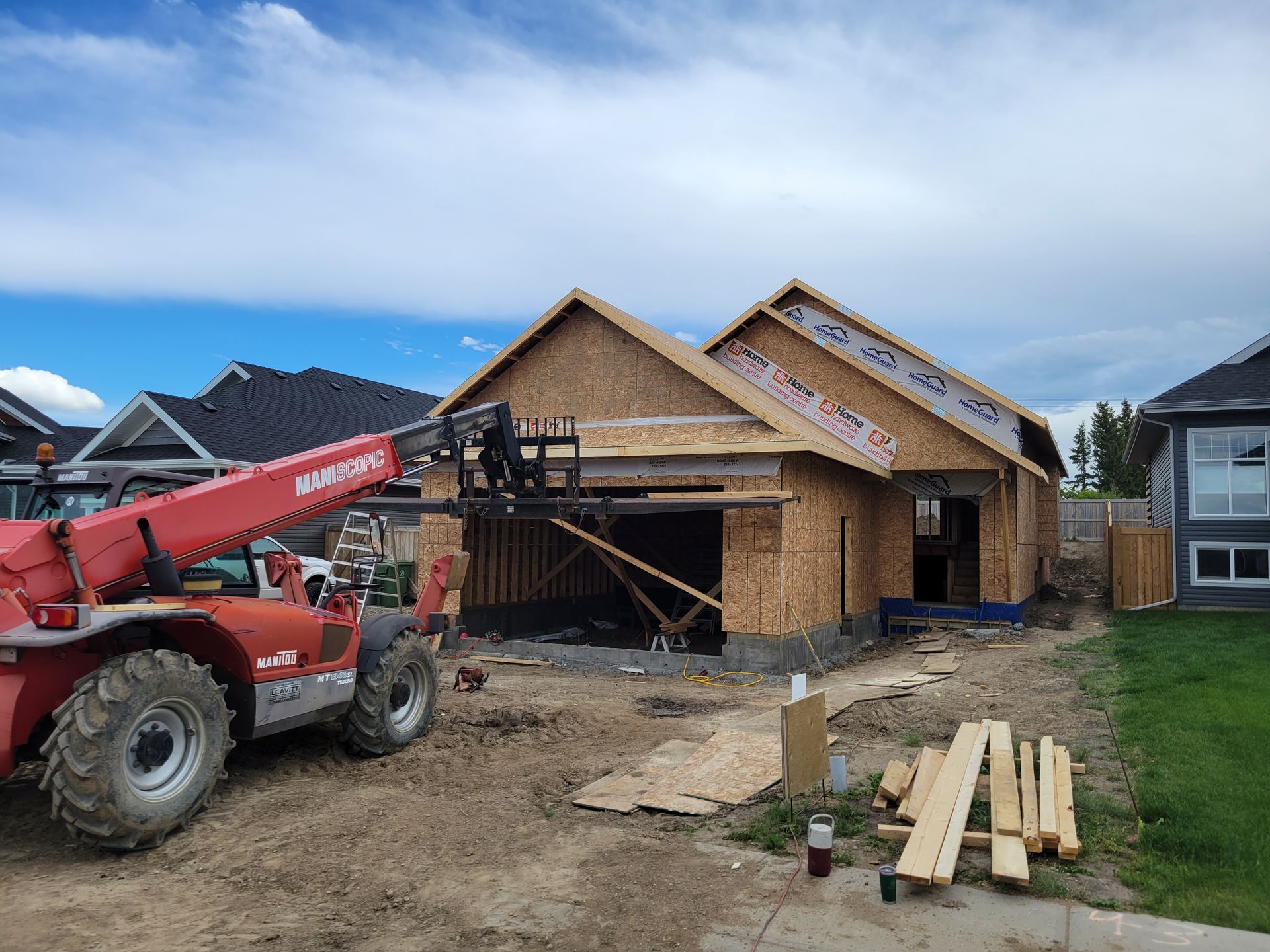 A red forklift is parked in front of a house under construction.