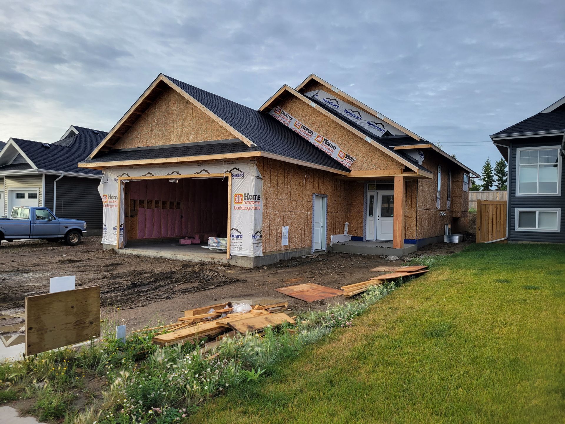 A house that is being built with a truck parked in front of it.