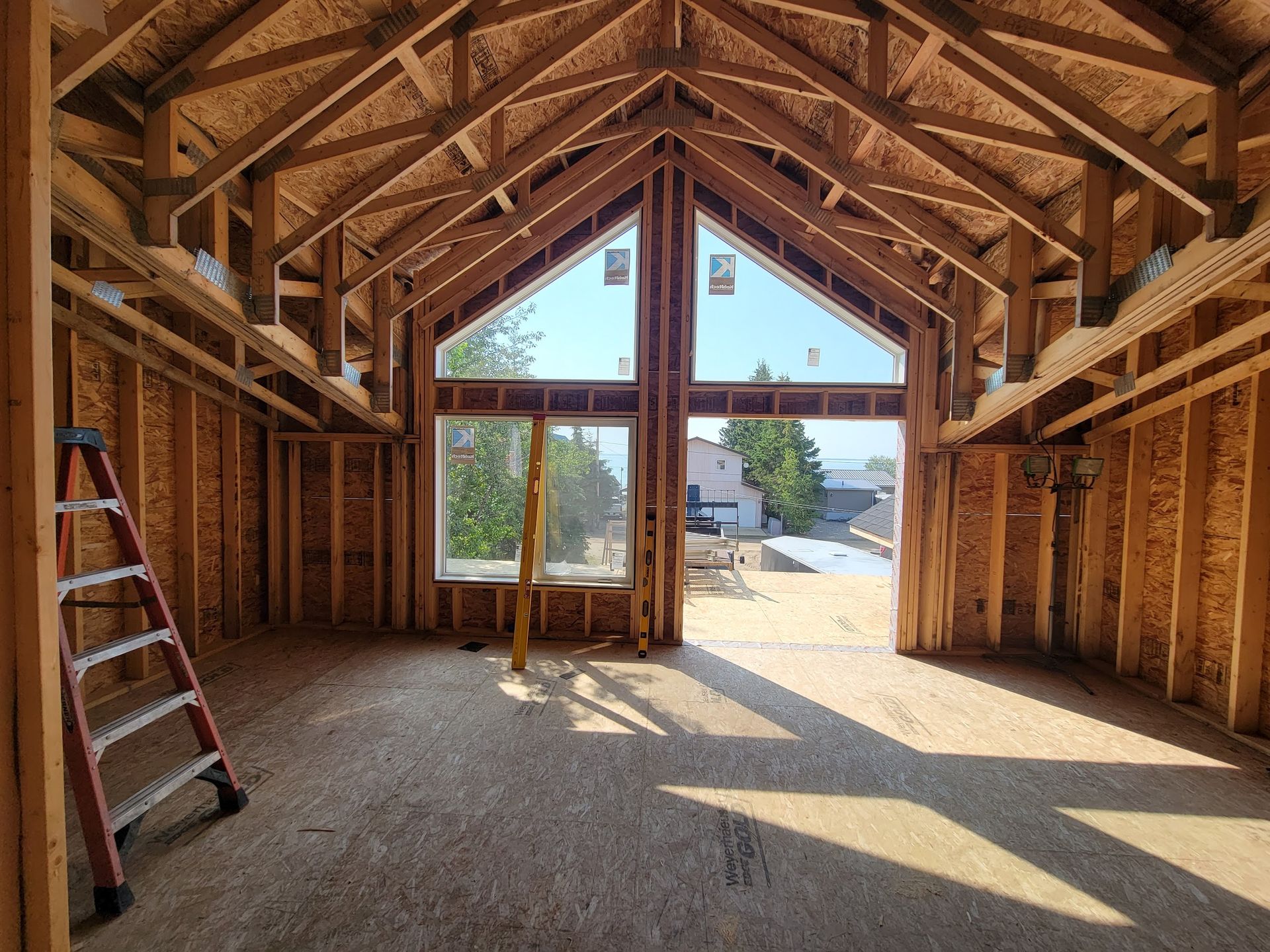 A ladder is sitting in the middle of a room in a house under construction.