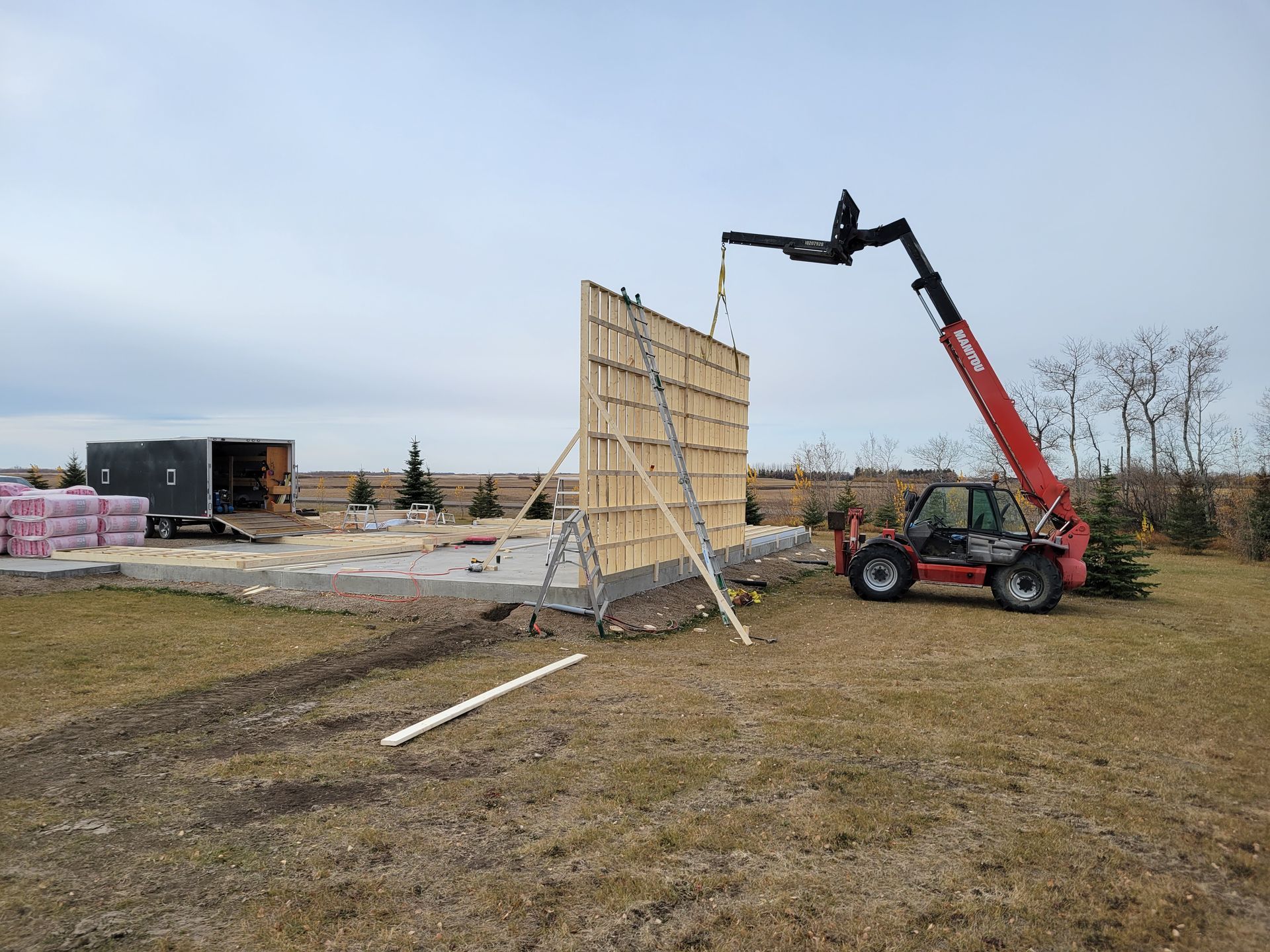 A forklift is lifting a large piece of wood in a field.