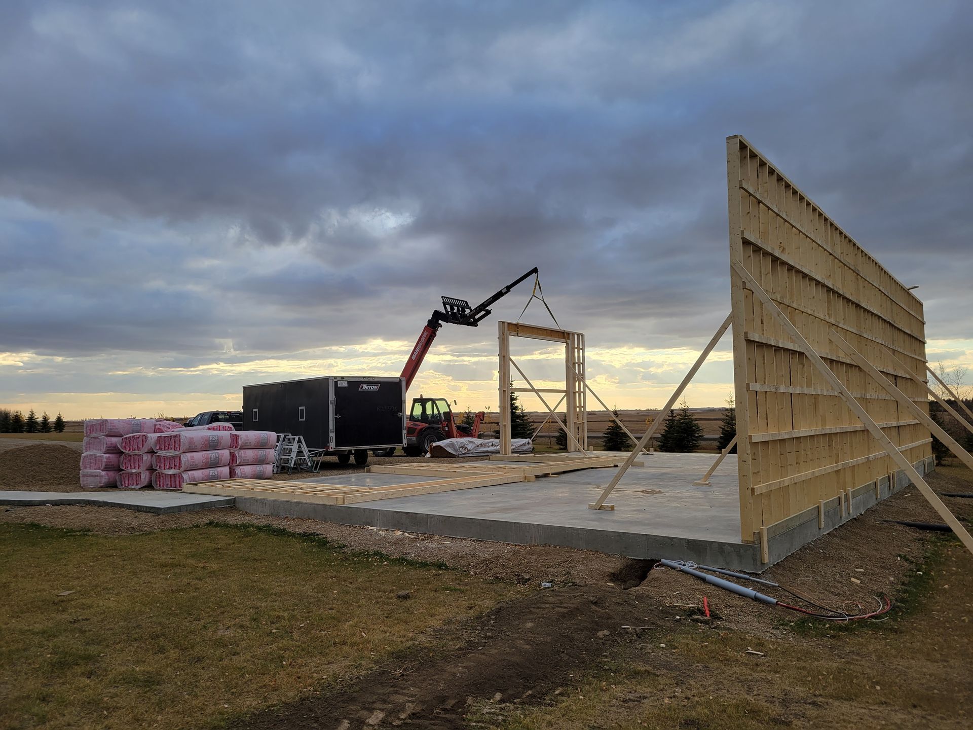 A crane is lifting a piece of wood in a field.