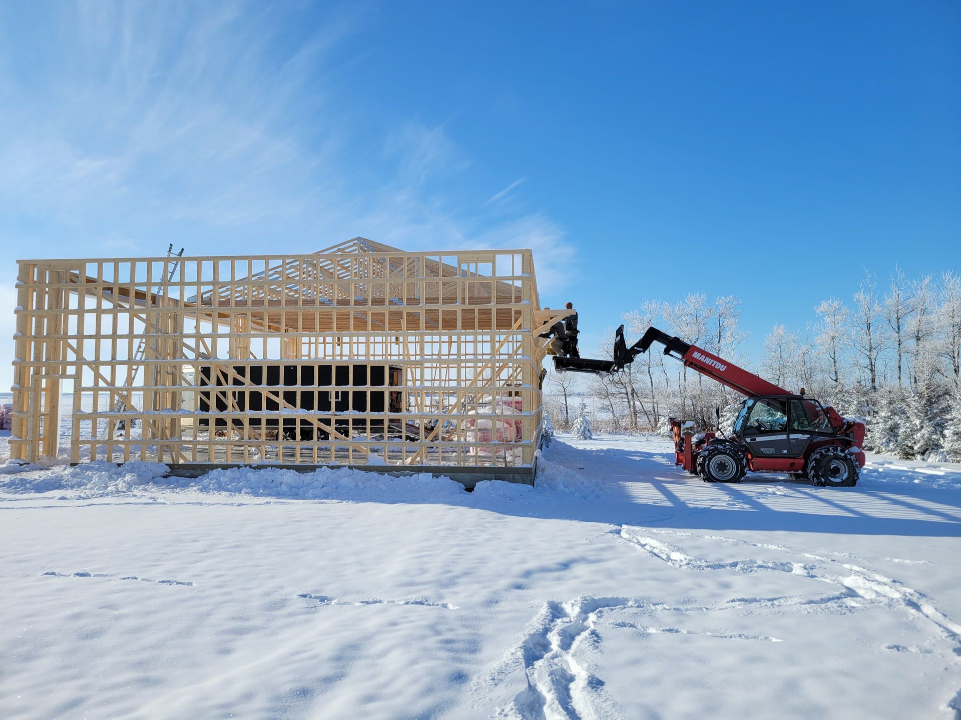 A crane is lifting a wooden structure in the snow.