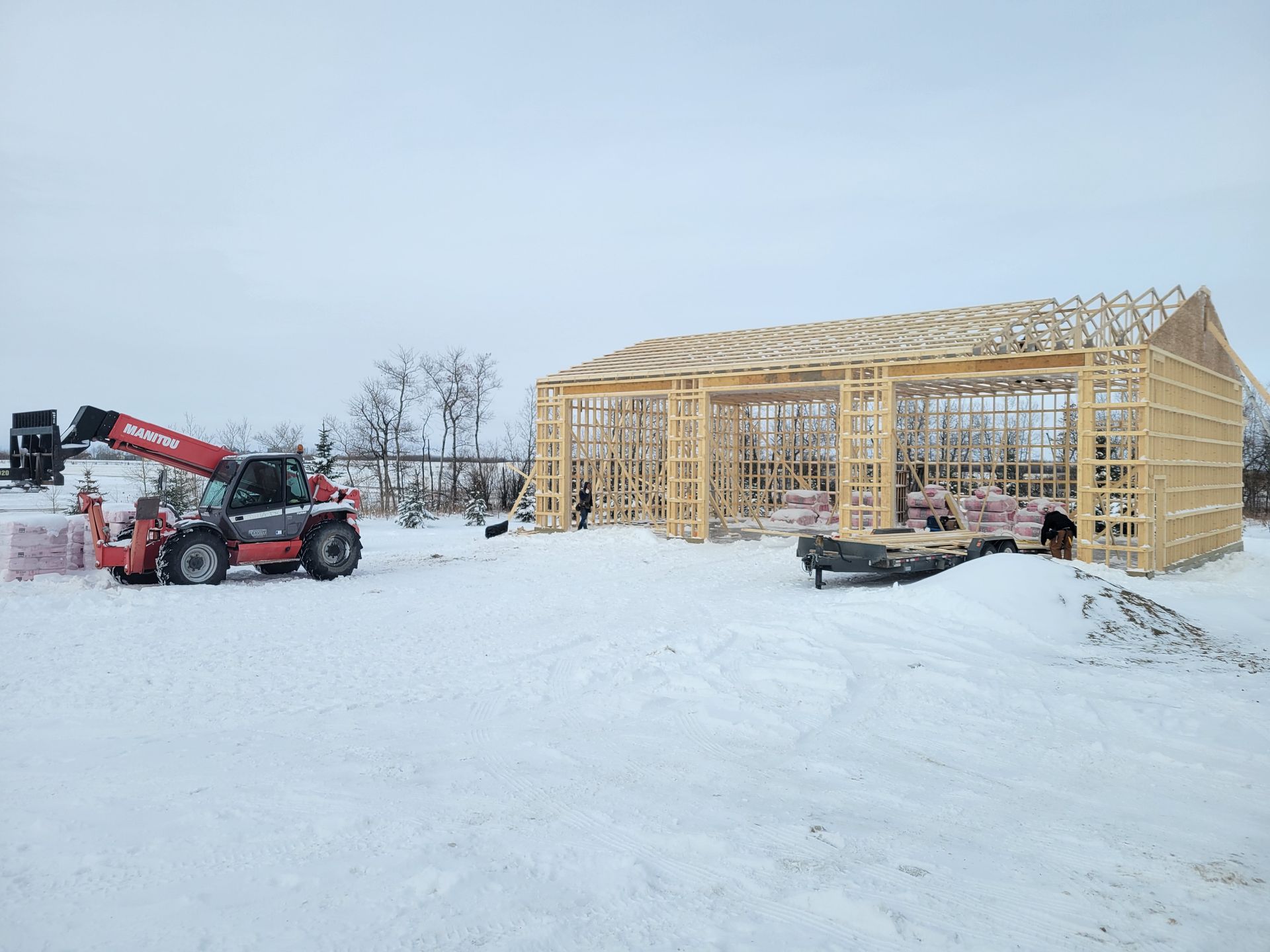 A large wooden structure is being built in the snow.