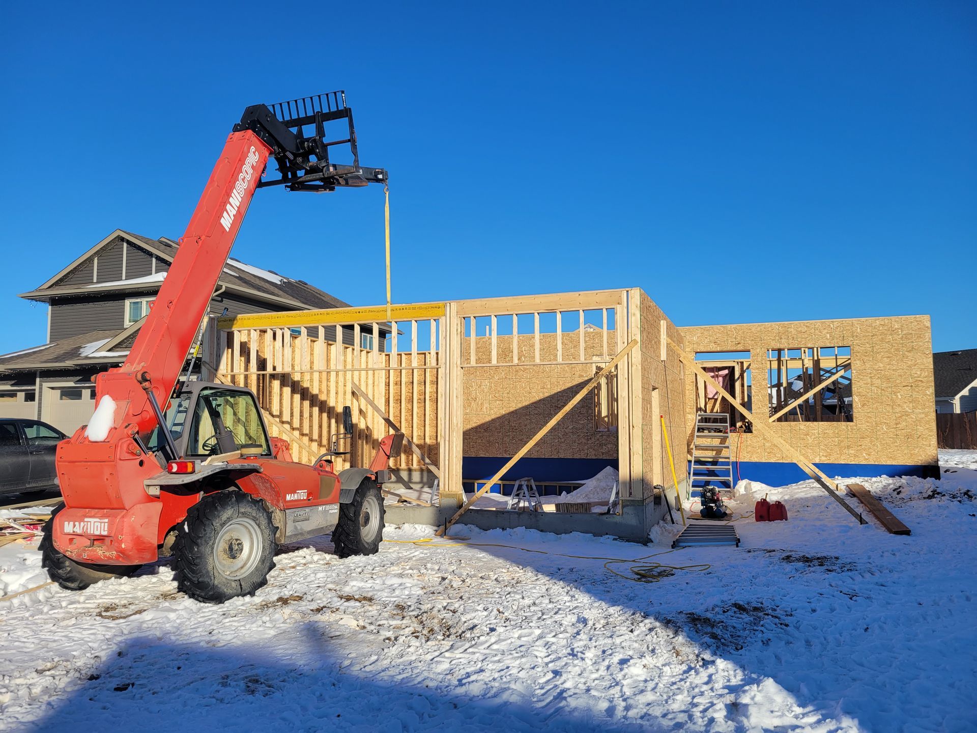 A red forklift is parked in front of a house under construction.
