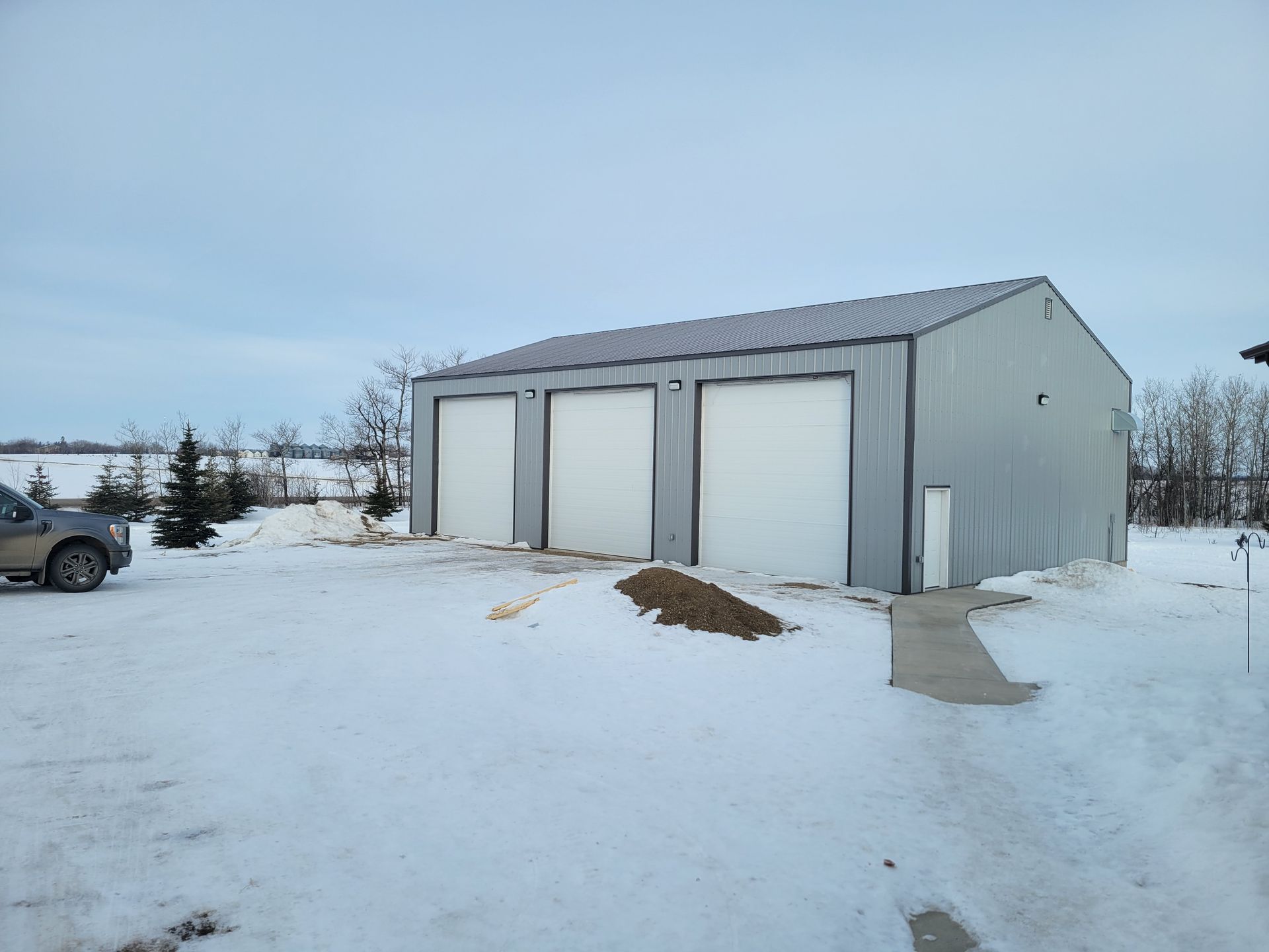 A car is parked in front of a garage in the snow.