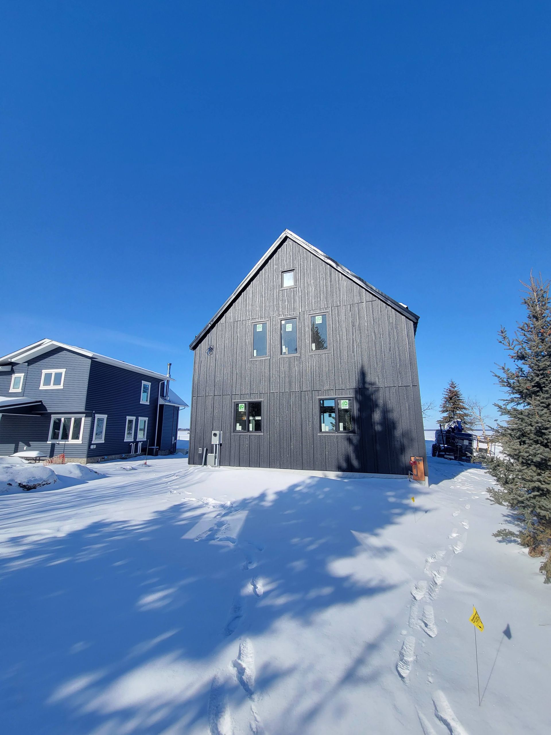 A large house is surrounded by snow on a sunny day.