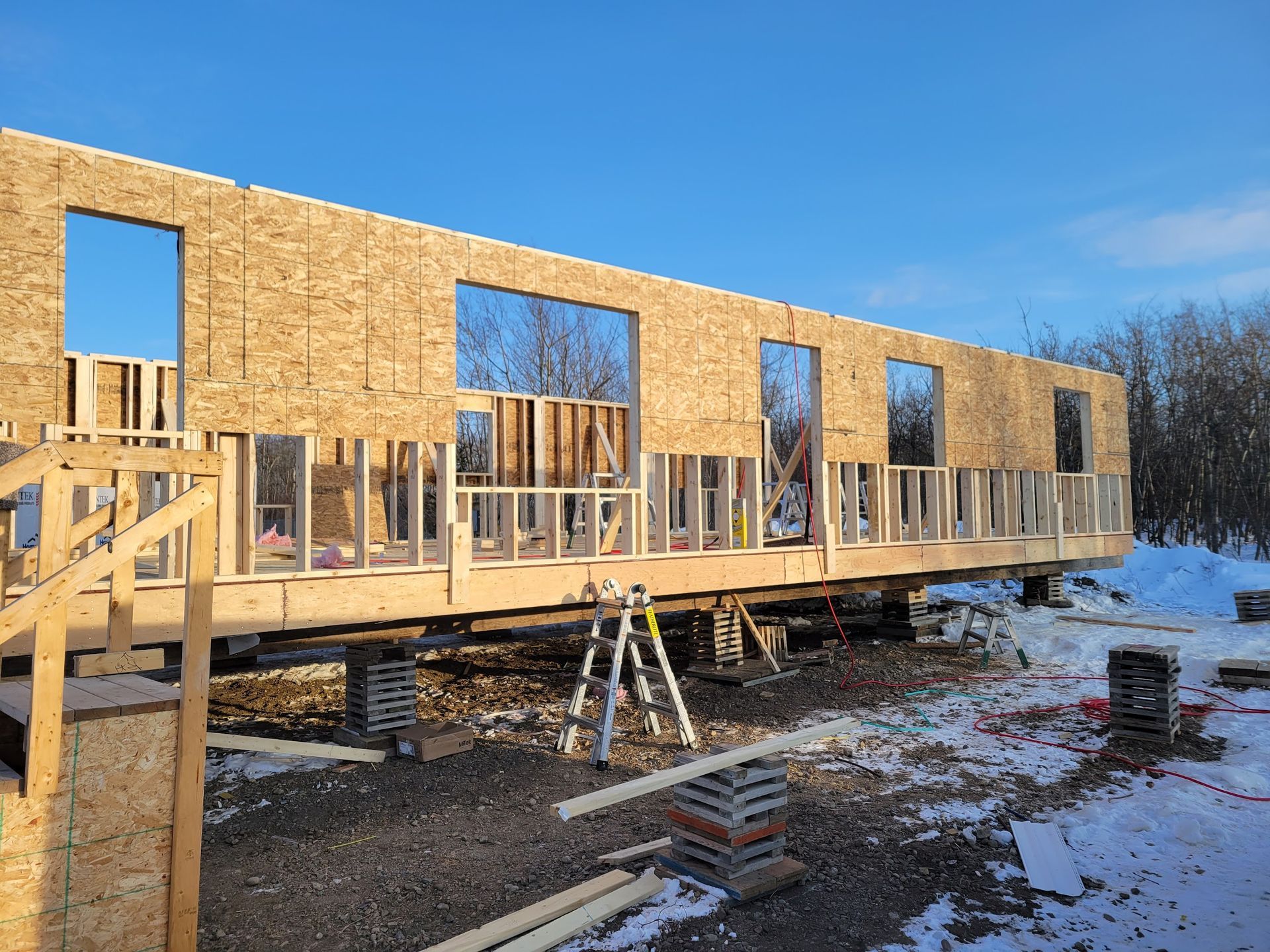 A large wooden house is being built in the snow.