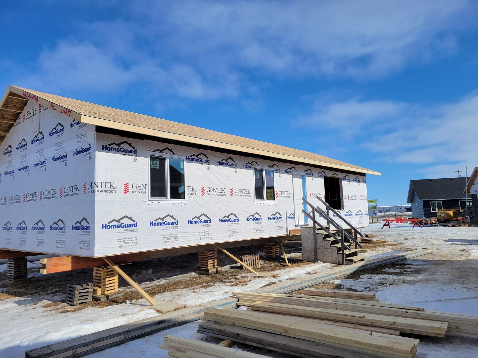 A house is being built in the snow with a blue sky in the background.