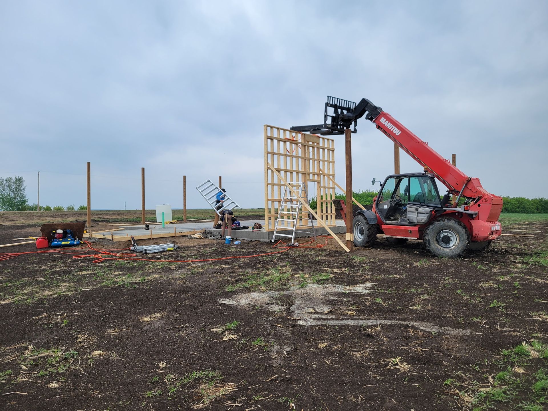 A red forklift is sitting in the middle of a dirt field.