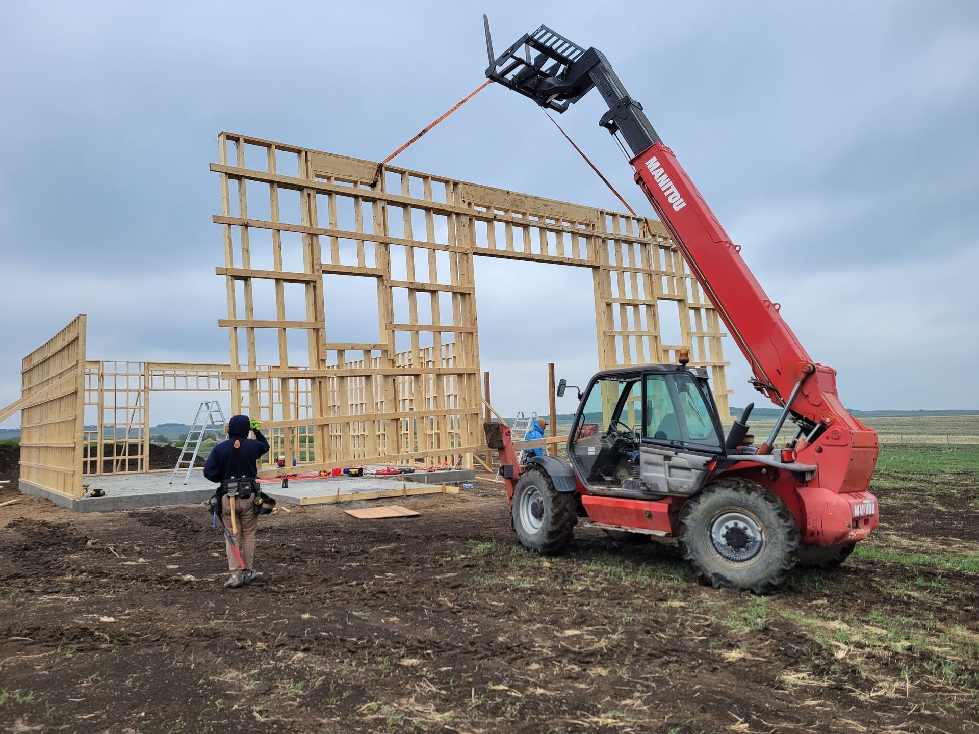 A red forklift is lifting a wooden structure in a field.