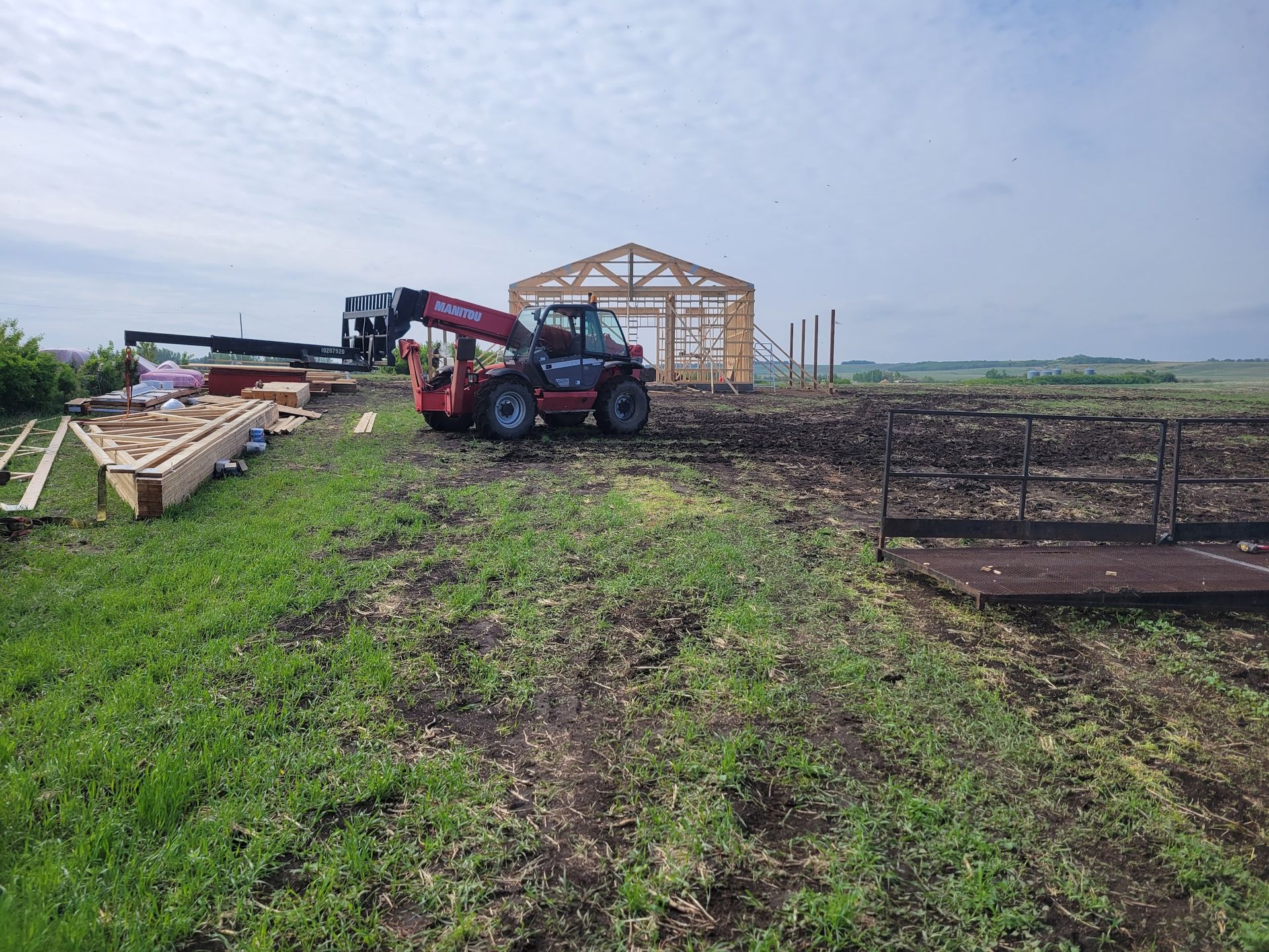 A red forklift is sitting in the middle of a grassy field.