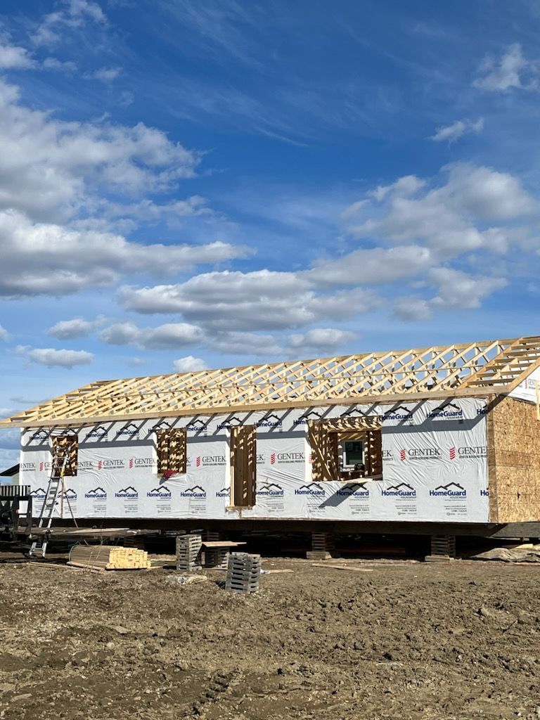 A house is being built in a field with a blue sky in the background.