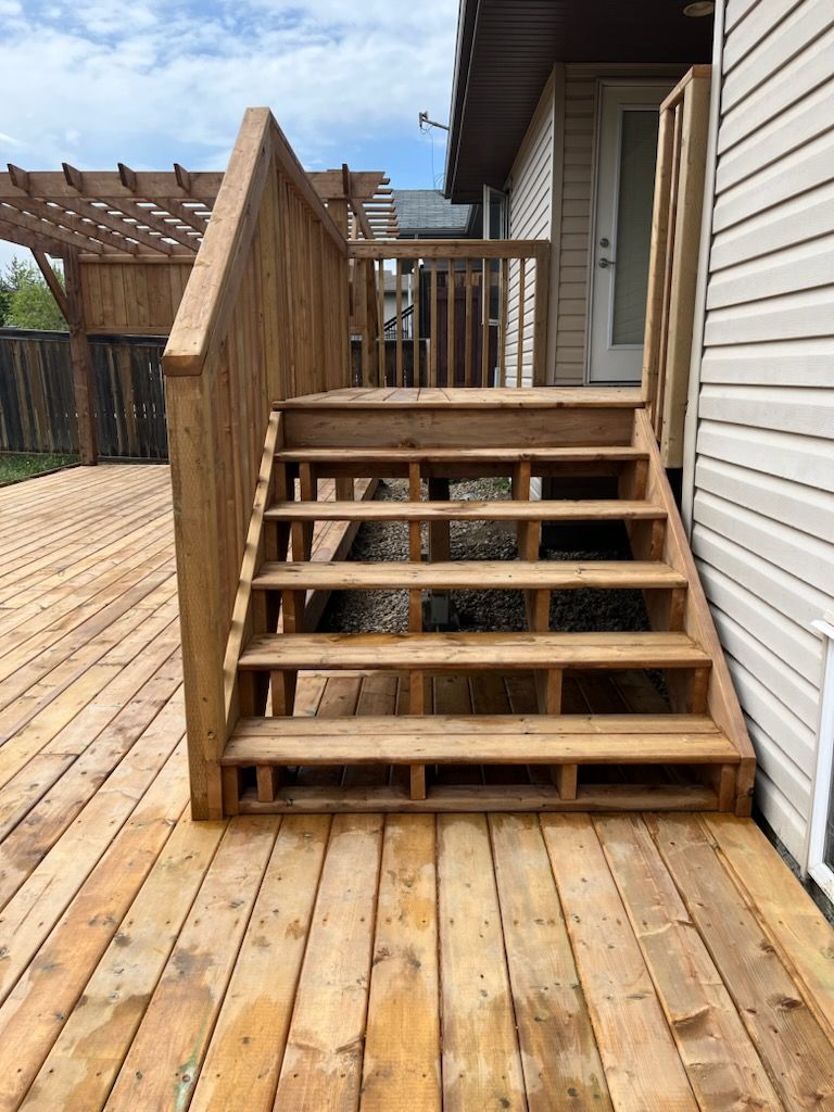 A wooden deck with stairs leading up to a house.