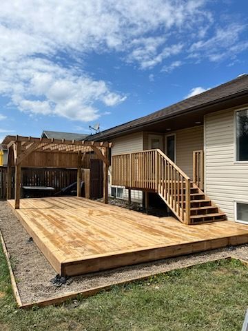 A wooden deck with stairs and a pergola in front of a house.