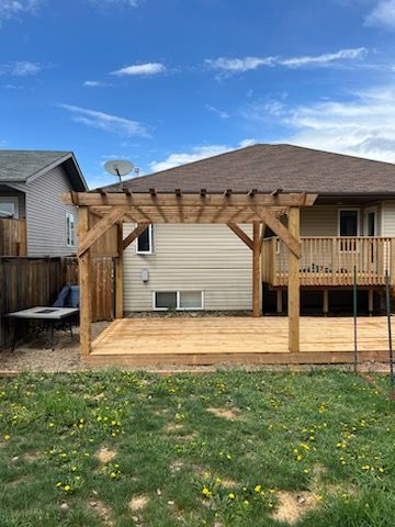 A wooden deck with a pergola in the backyard of a house.