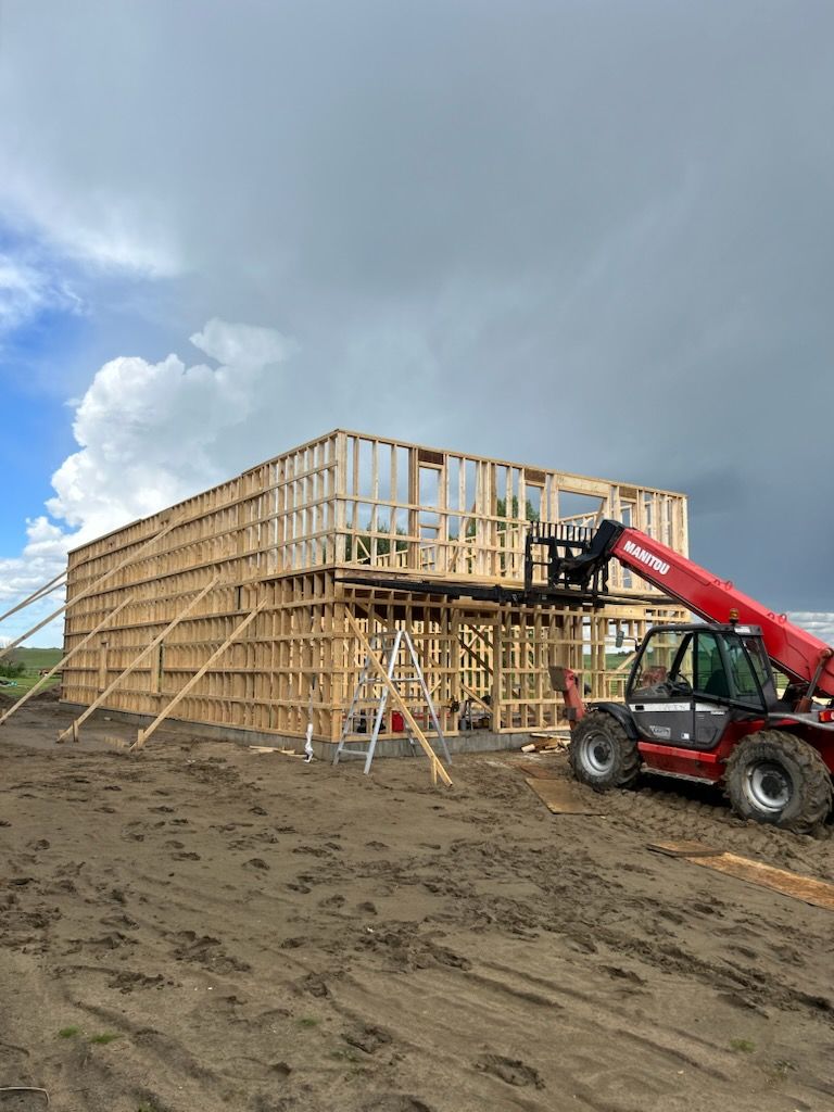 A red forklift is sitting in front of a building under construction.