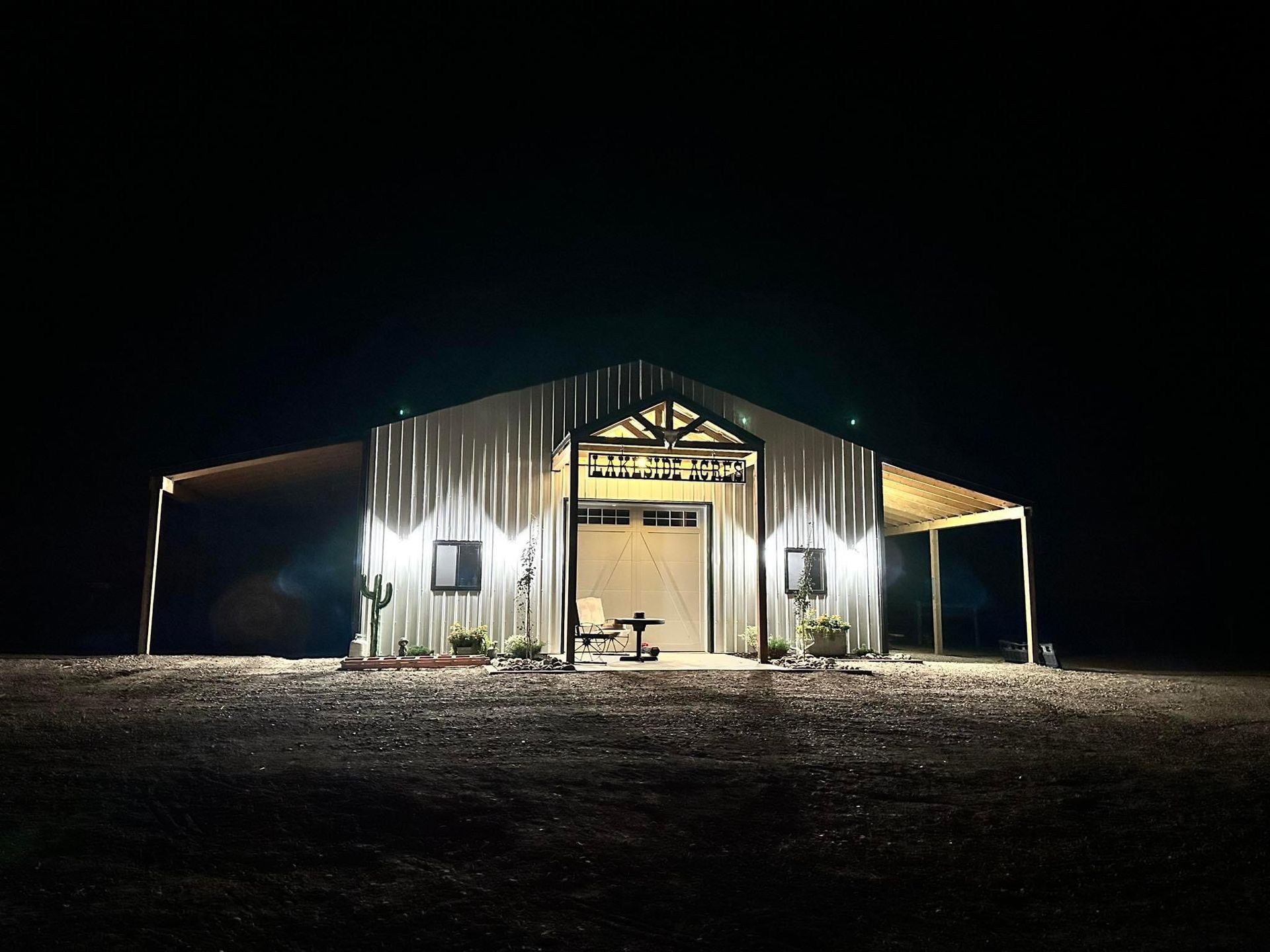A barn is lit up at night in a field.