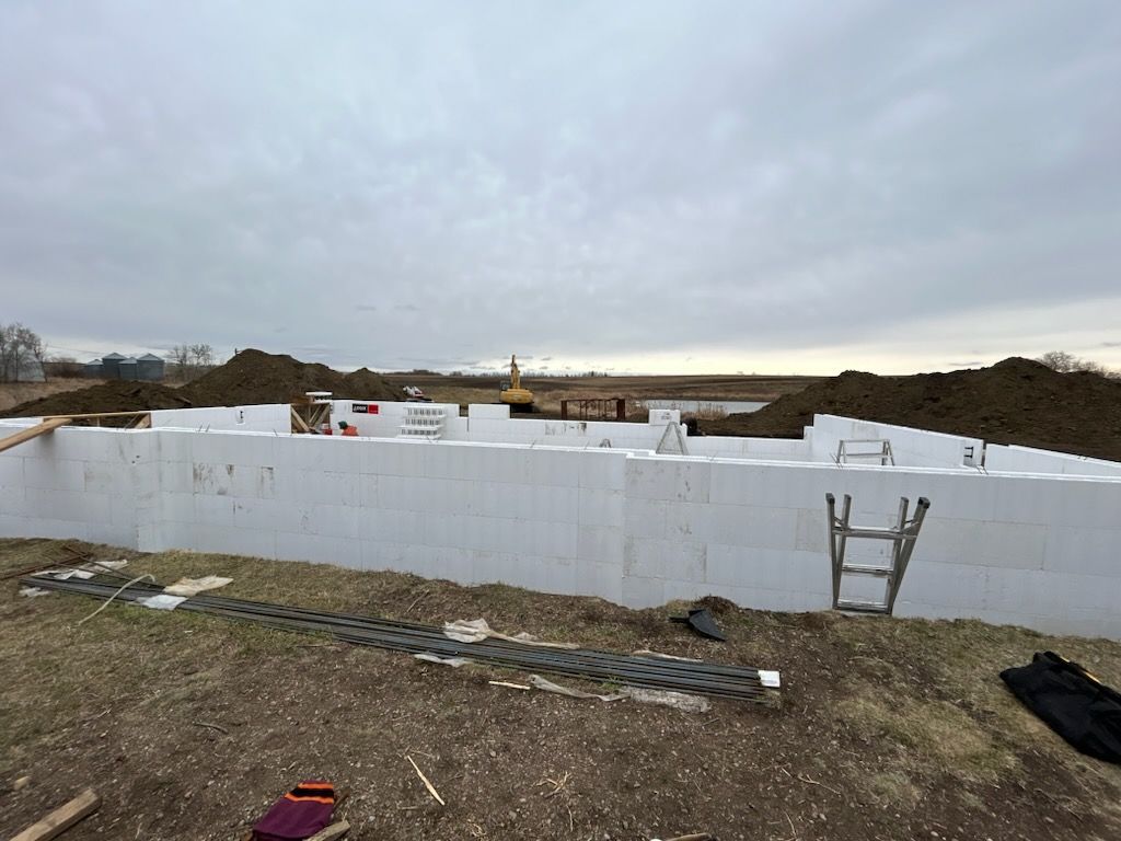 A large white wall is being built in a field with a ladder.