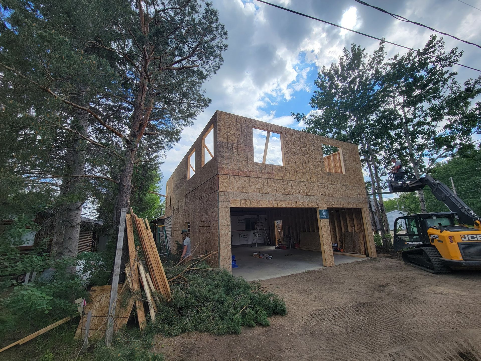 A house is being built with a tractor parked in front of it.
