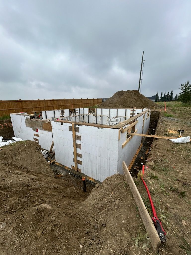 A large concrete wall is being built in a dirt field.