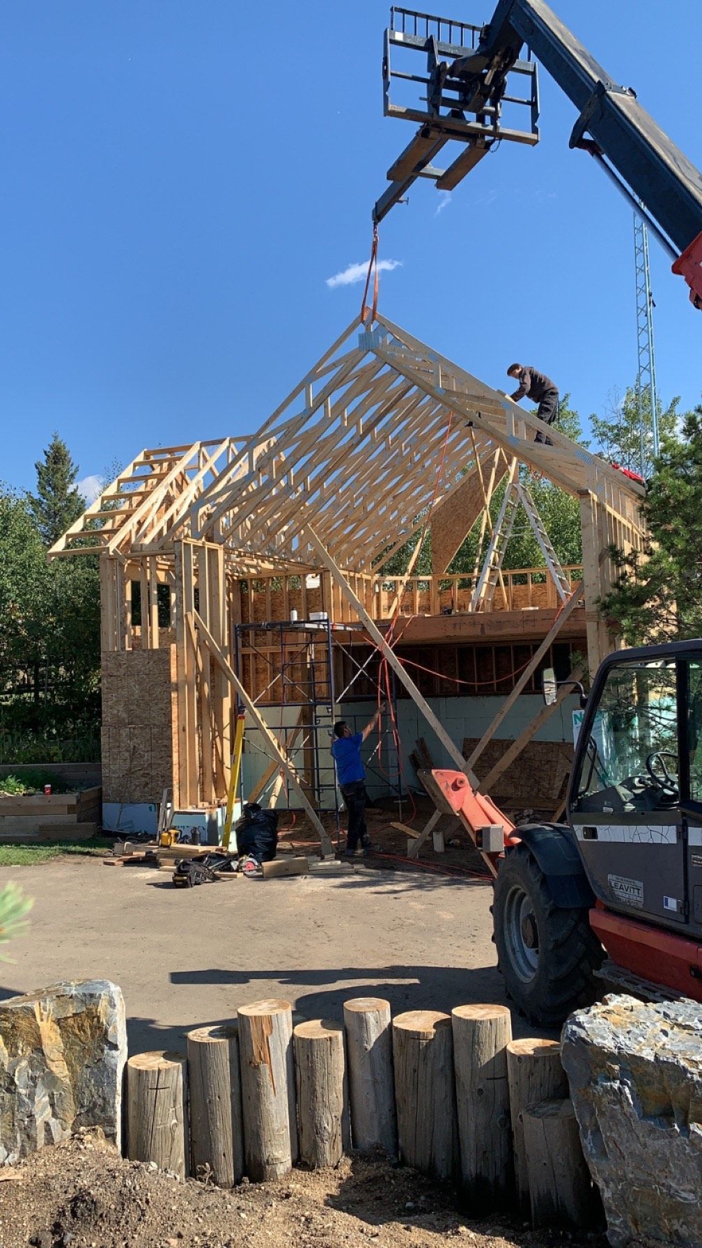 A house is being built with a crane and a forklift.