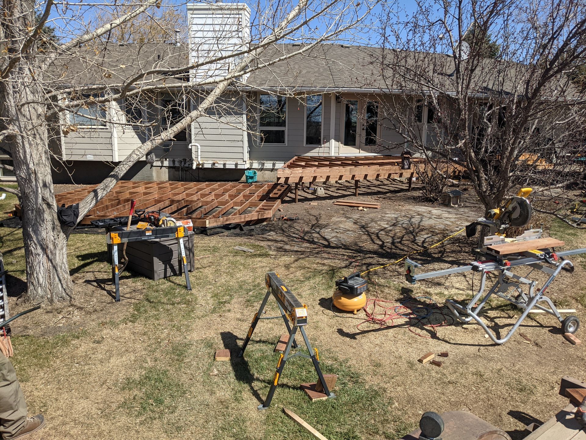 A wooden deck is being built in the backyard of a house.