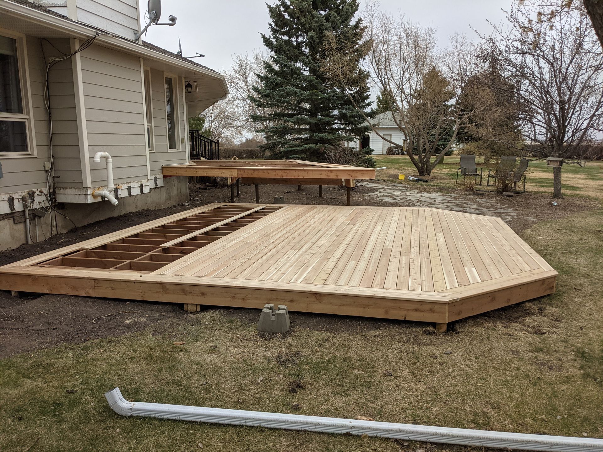 A wooden deck is being built in the backyard of a house.