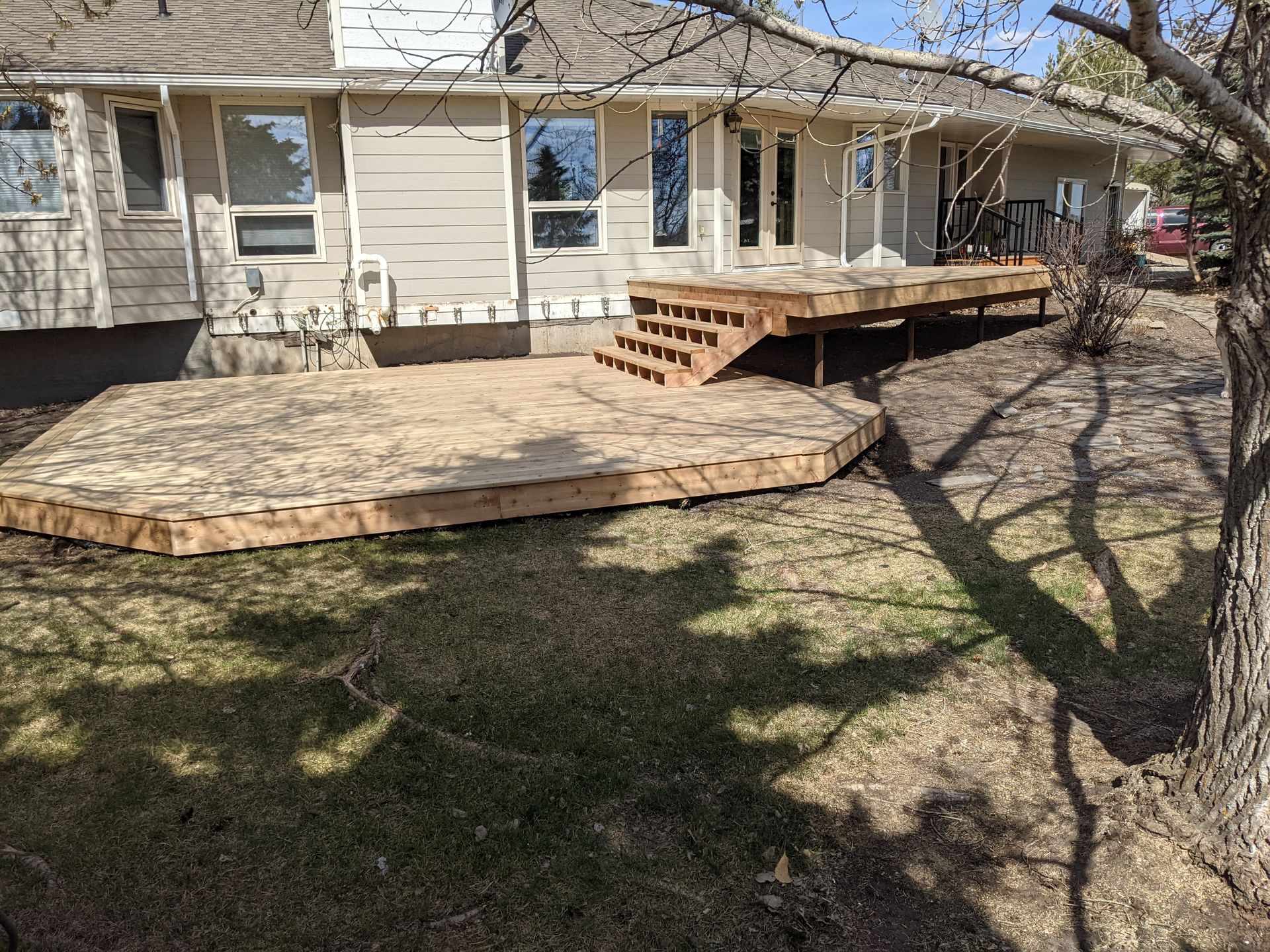 A large wooden deck is in the backyard of a house.