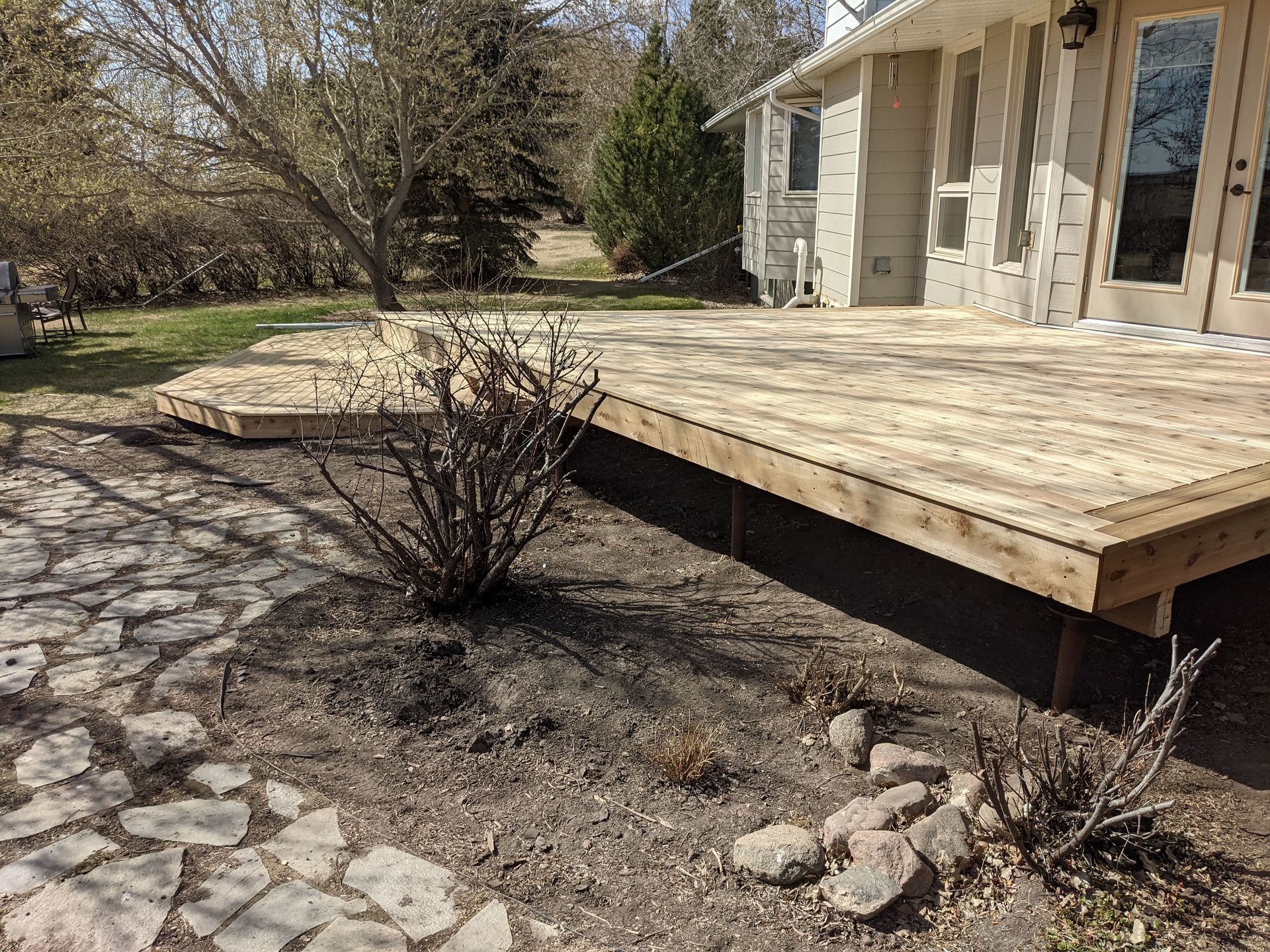 A wooden deck is sitting in the dirt in front of a house.