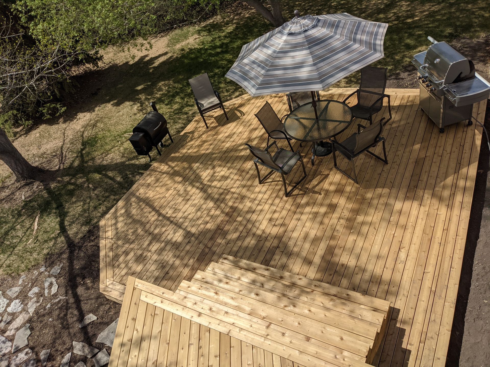 An aerial view of a wooden deck with a table and chairs and an umbrella.