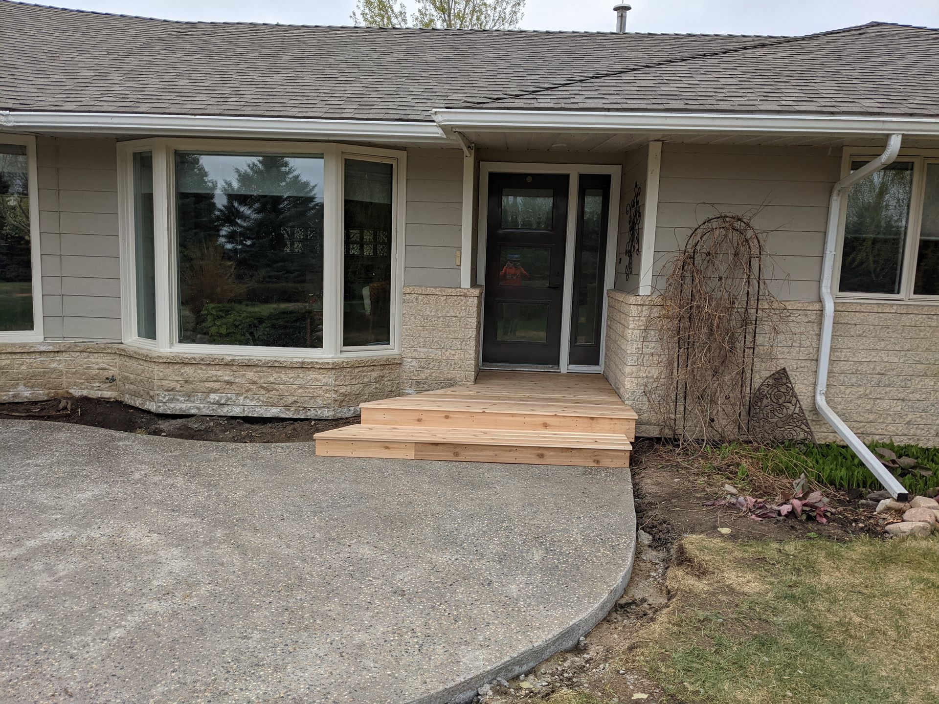 A house with a concrete driveway and wooden steps leading to the front door.