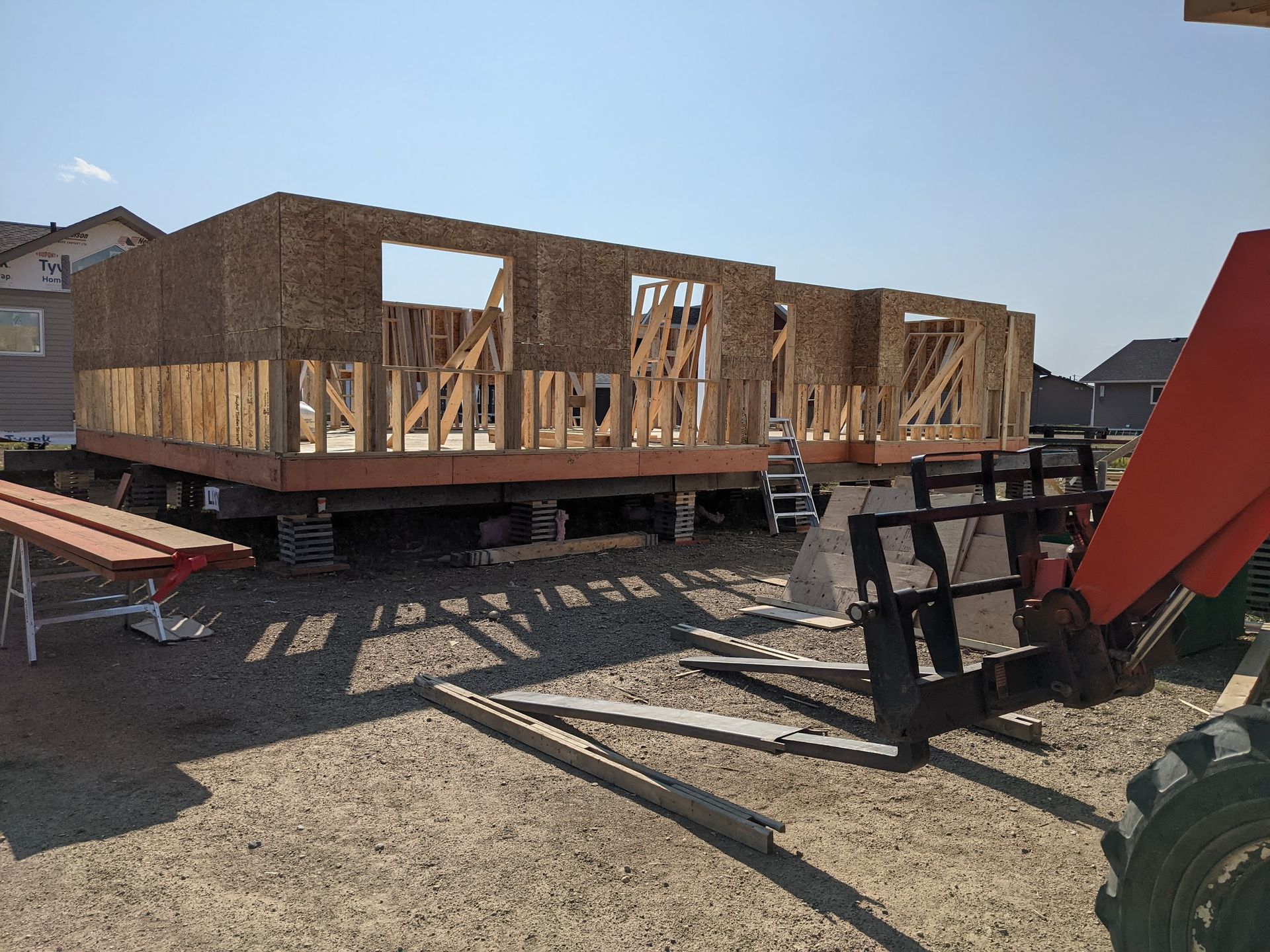 A house is being built with a forklift in the foreground