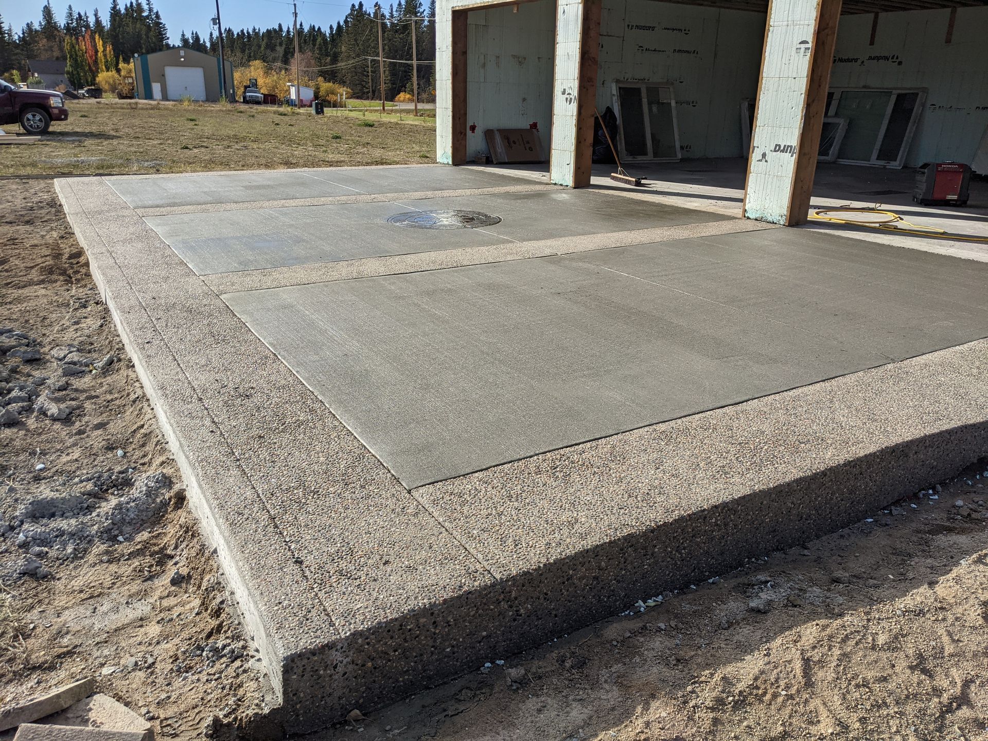 Concrete patio with a raised perimeter, adjacent to a building under construction.