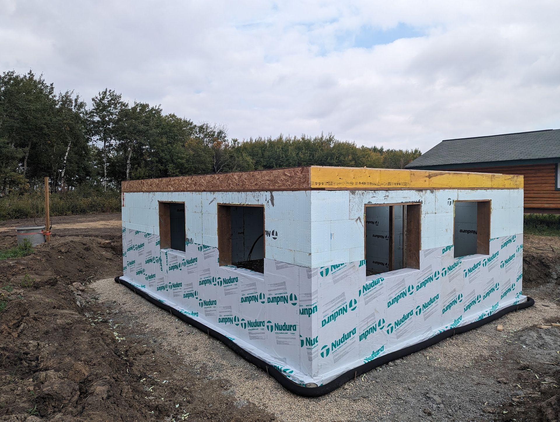 A small house is being built in a dirt field.