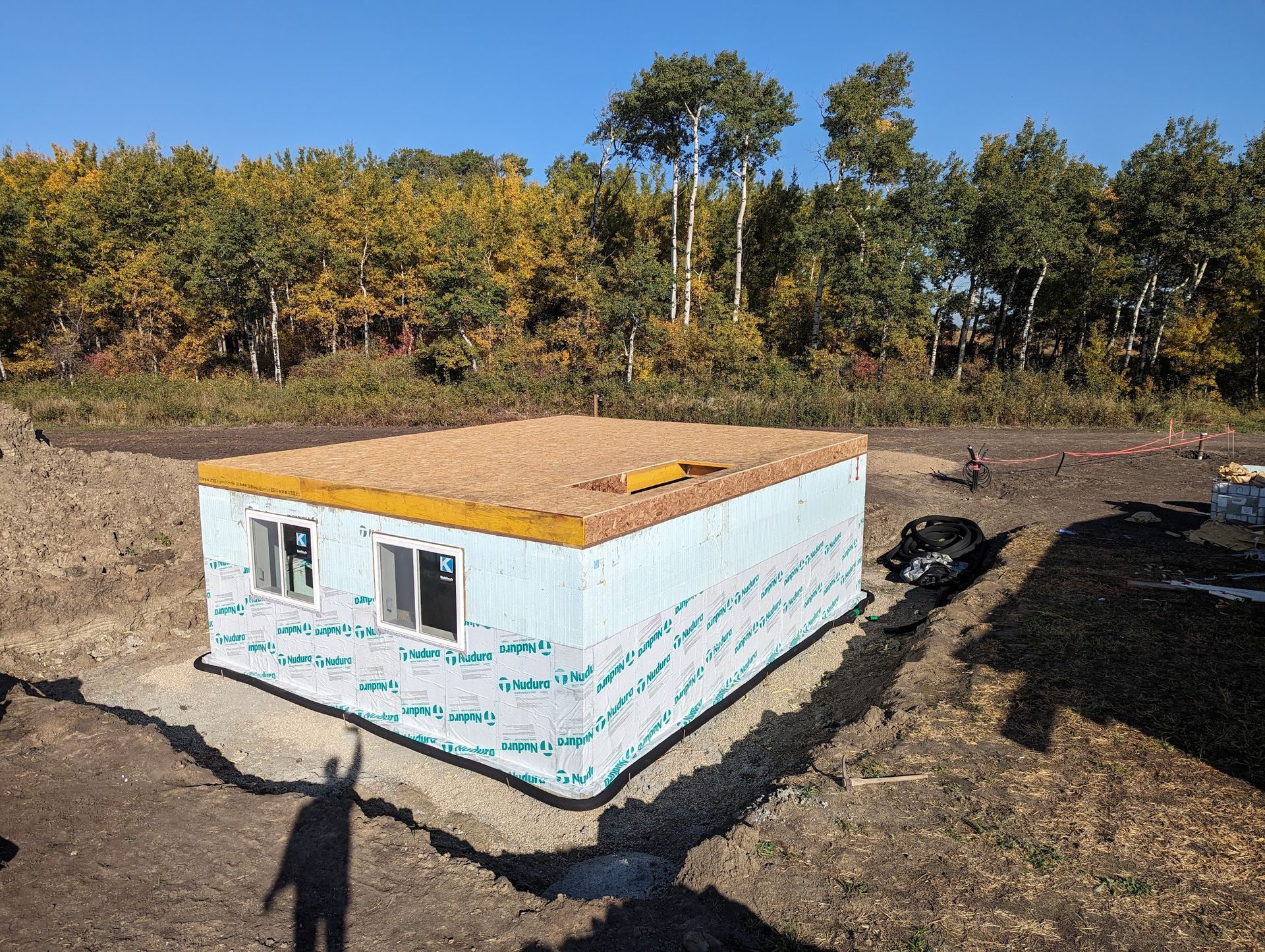 A small house is being built in the middle of a dirt field.