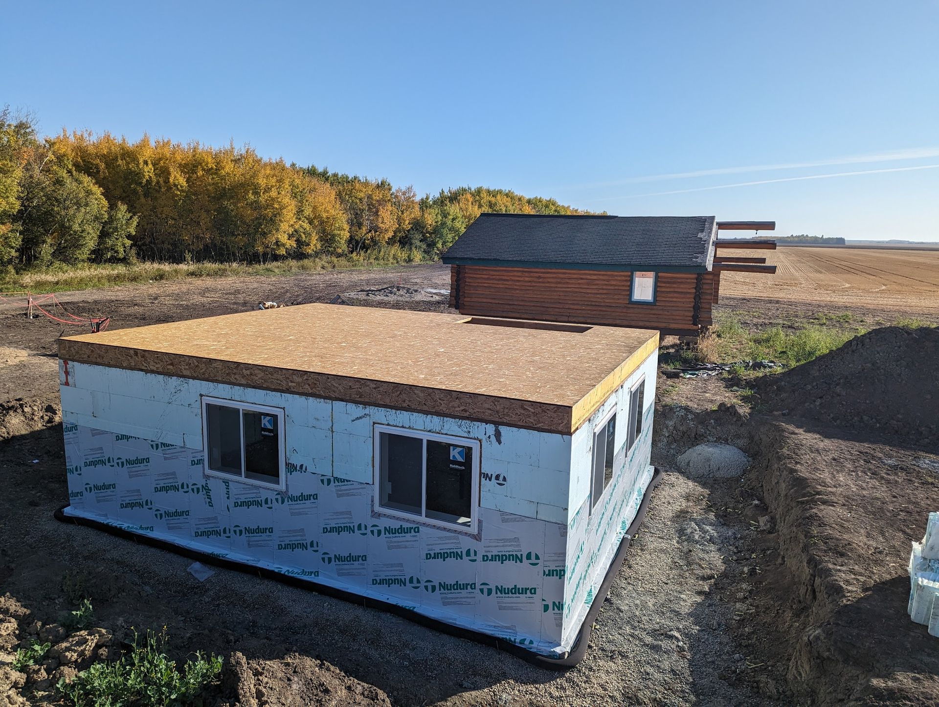 A small house is being built in the middle of a field.