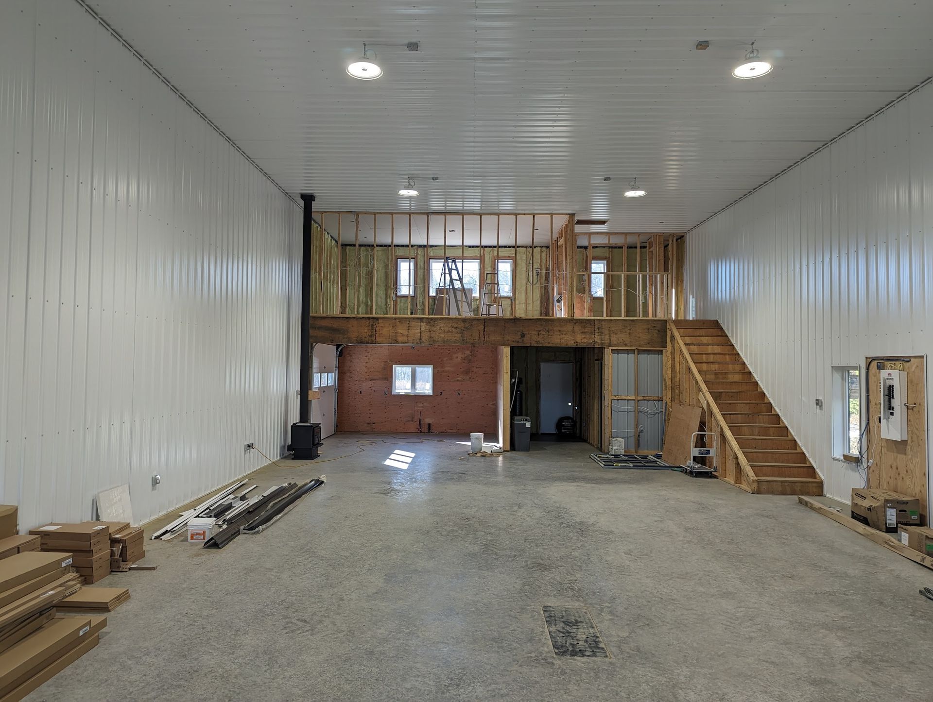 The inside of a building under construction with stairs leading up to the second floor.