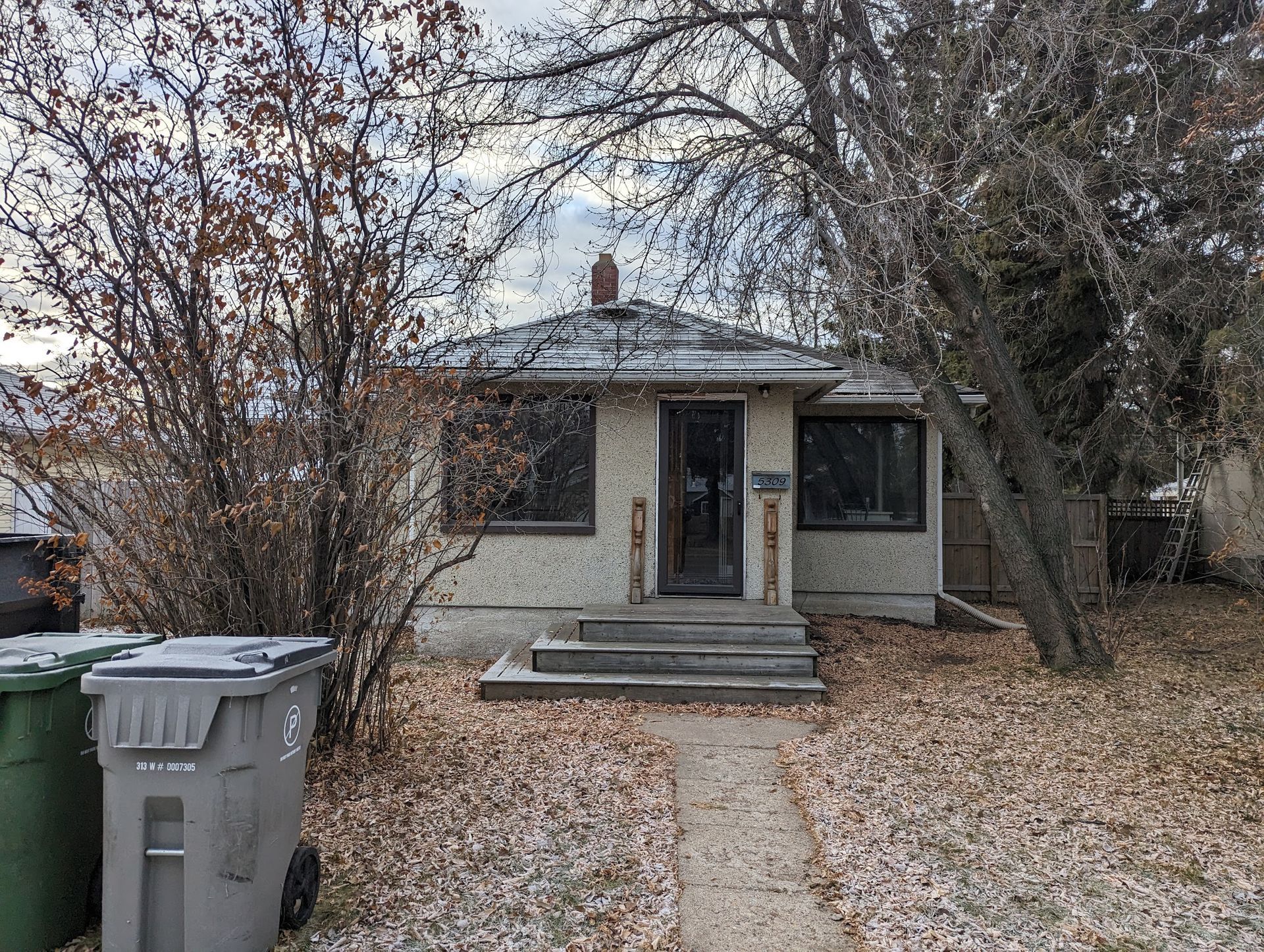A small house with a lot of trash cans in front of it.