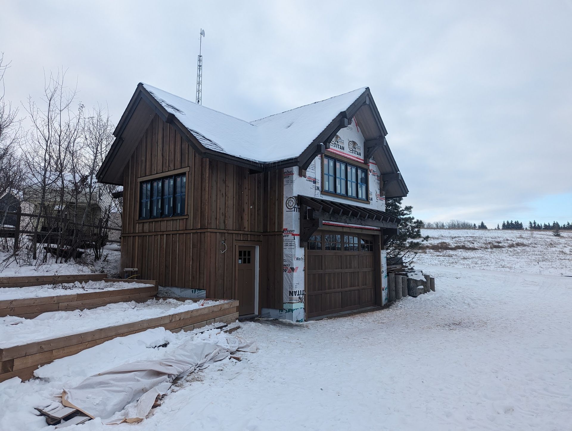 A small wooden house with a garage in the snow.