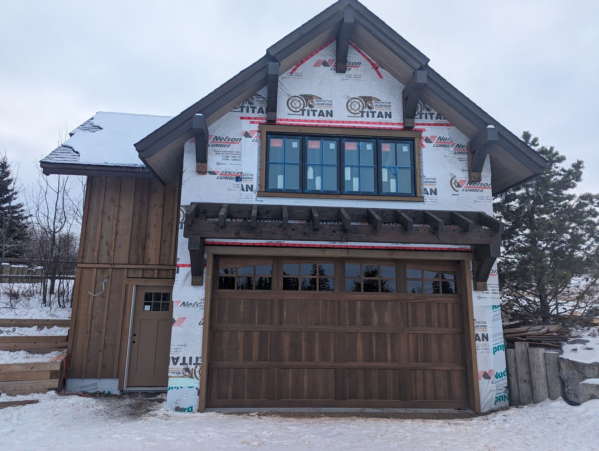 A house with a wooden garage door is covered in snow